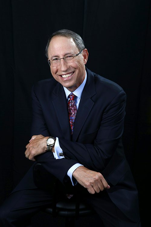 Portrait of David Fischell sitting with his arms crossed