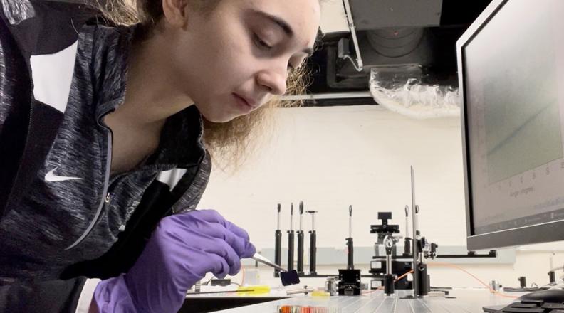 Glovia Davidova is wearing neoprene gloves  working careefully with lab equiptment on a table.