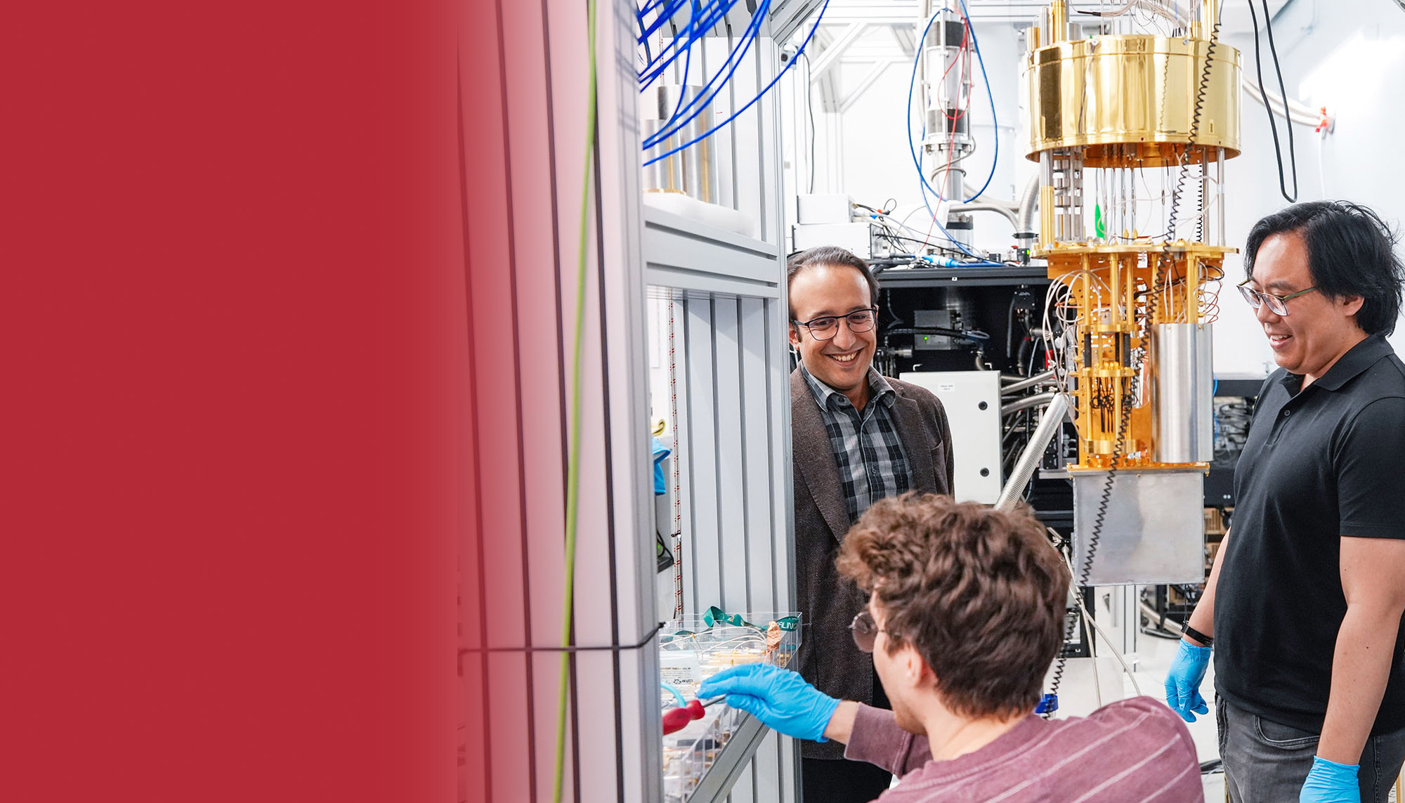 Professor Fatemi and two students stand near a cryostat.