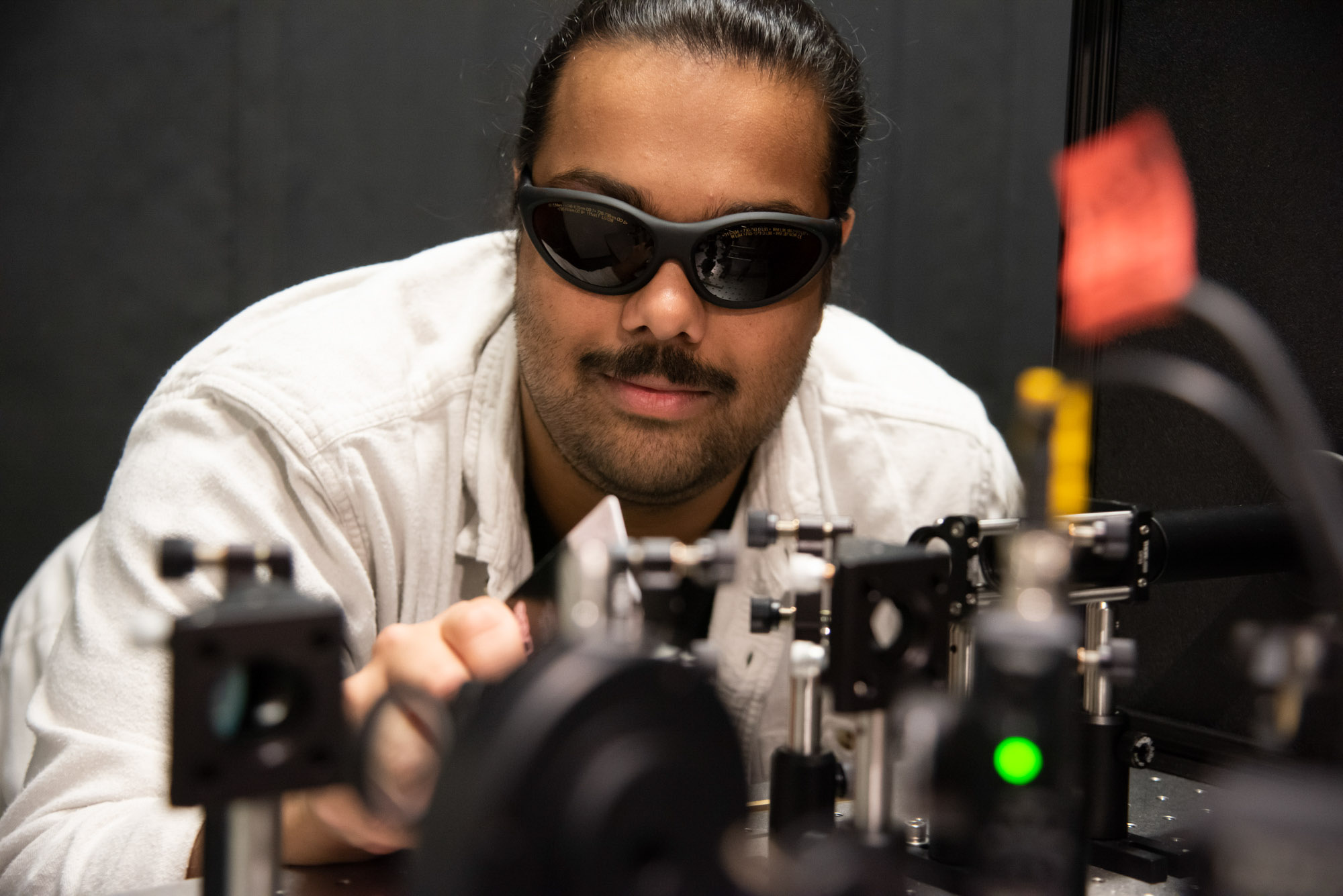 Graduate student works with lasers in optics lab in Weill Hall