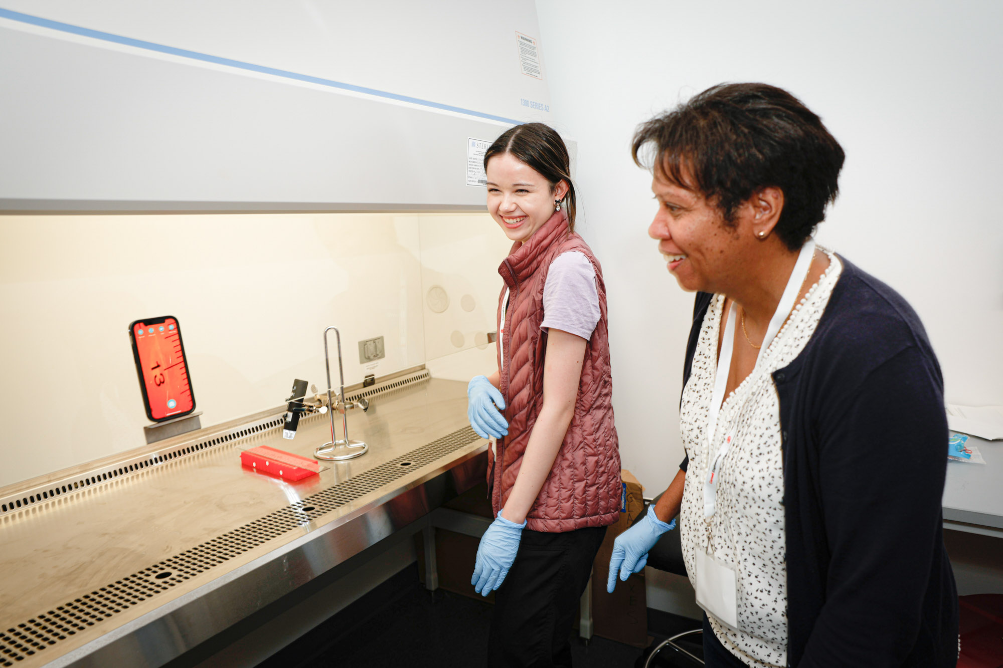 Shivaun Archer and student use a digital microscope in a lab fume hood to project an image onto a tablet.