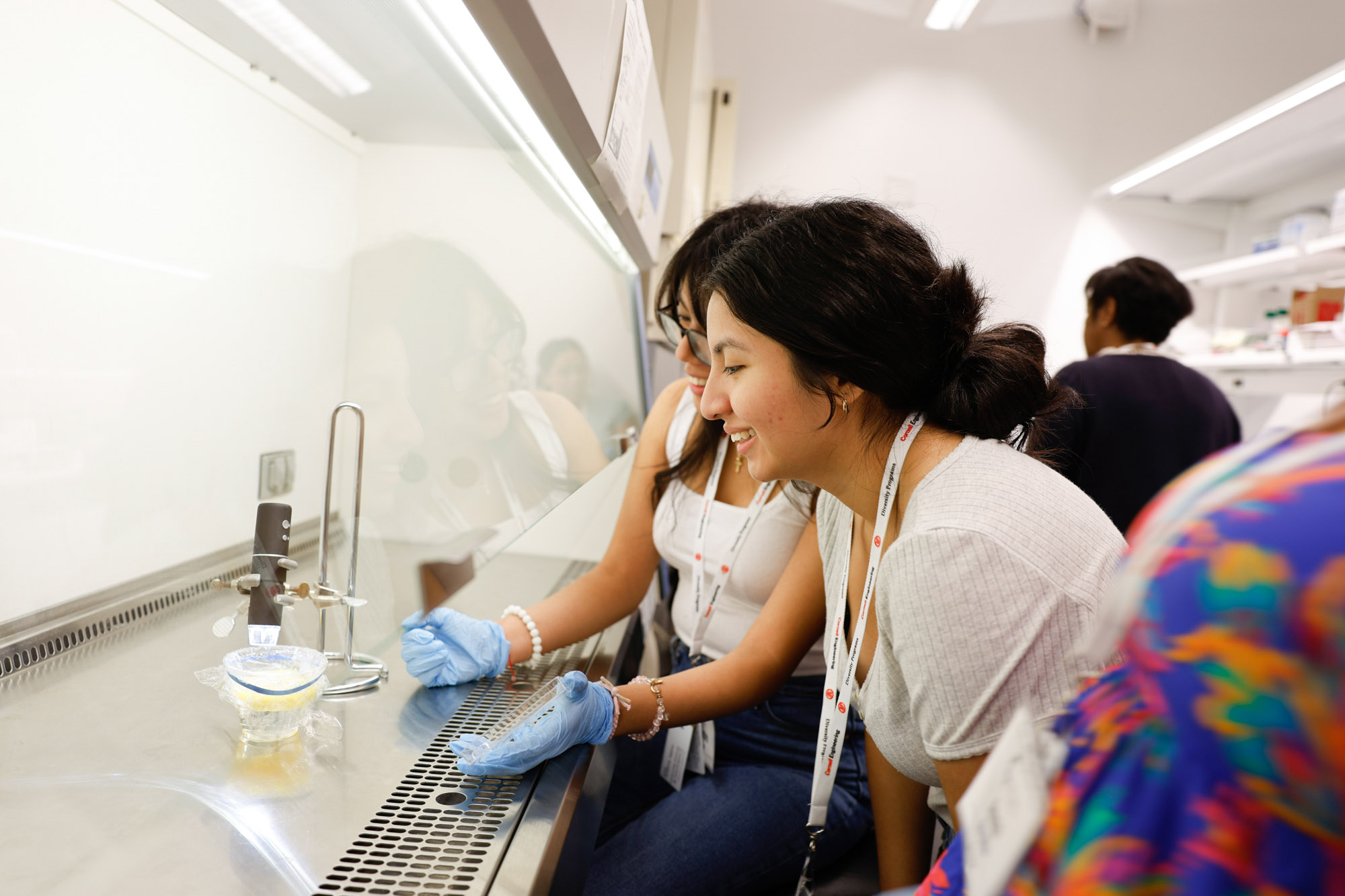 High school students work together on experiment at fume hood in Weill Hall wet lab.