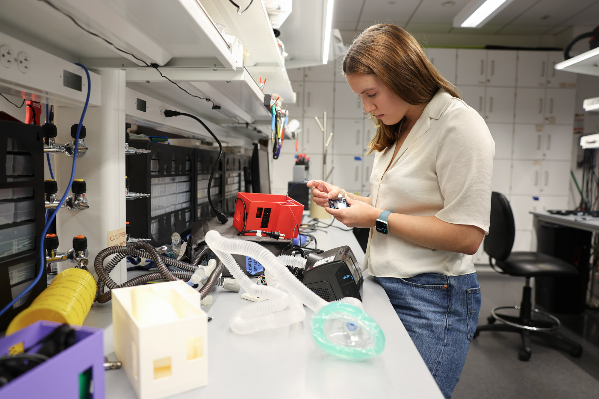 Undergraduate student Emma Taigounov at bench working on senior design project, a continuous positive airway pressure (CPAP) device accessory in Weill Hall.