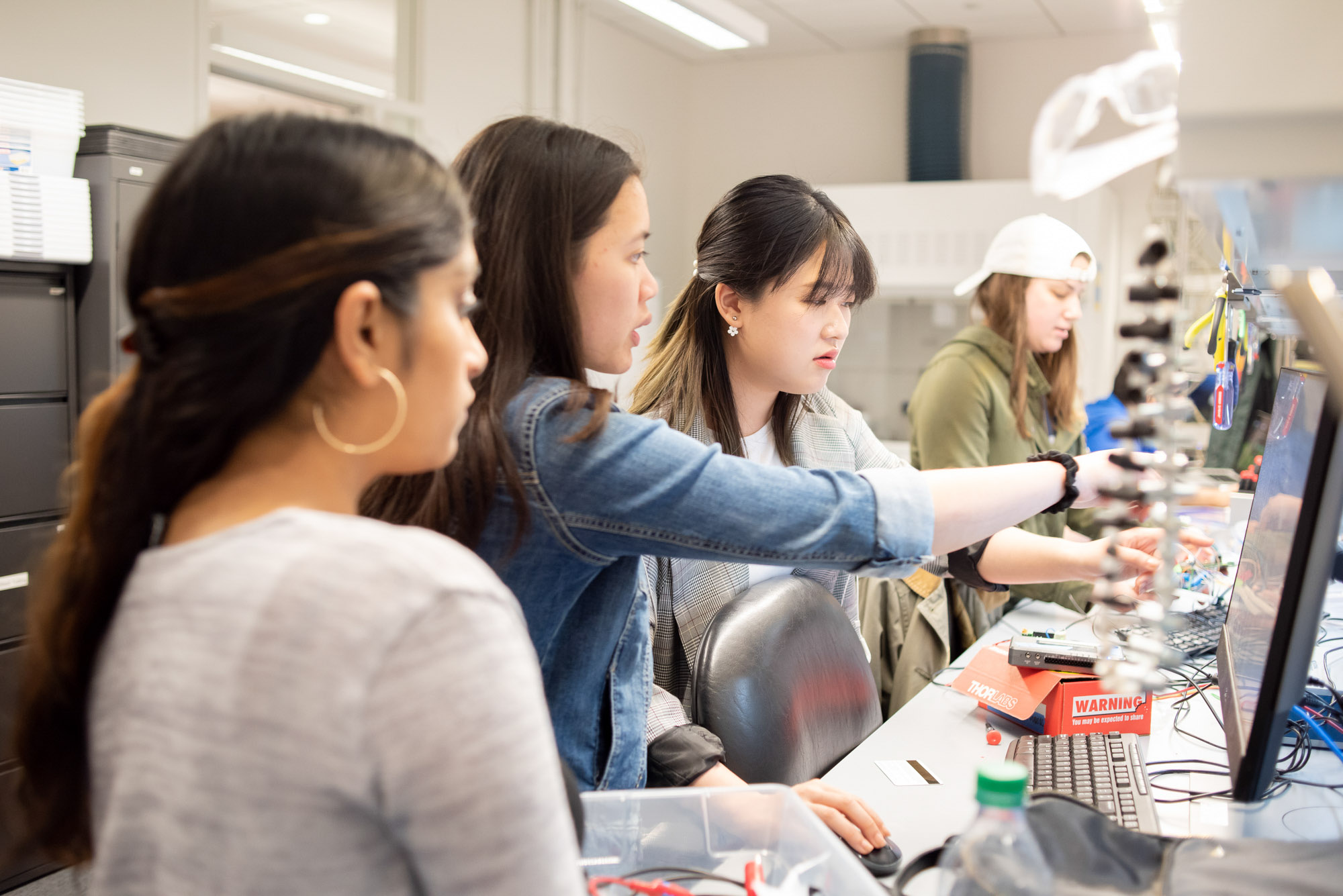 Four students researchers look at a computer screens in the BME M.Eng. Fab Lab