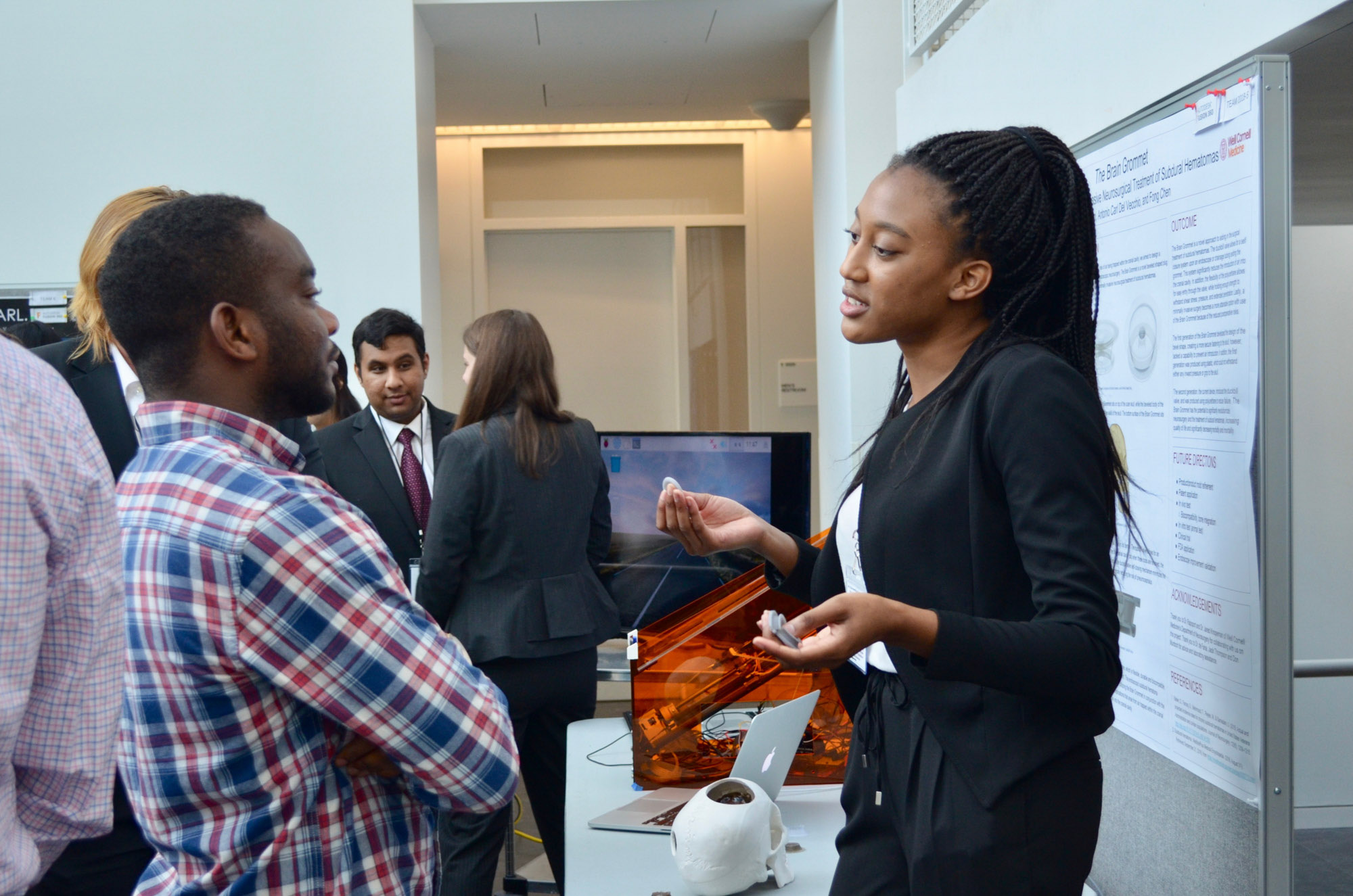 A student describes their project to another student during the poster session of the BME Industry Day M.Eng. Showcase.