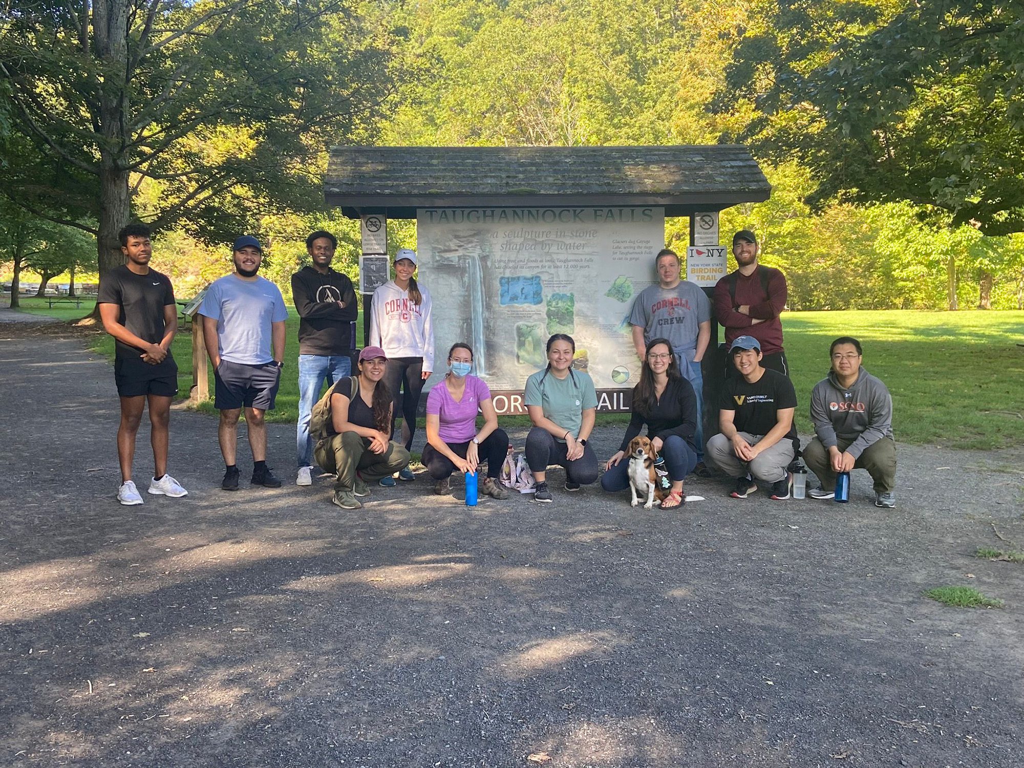 graduate students stand by Taughannock Falls sign at start of hiking trail.