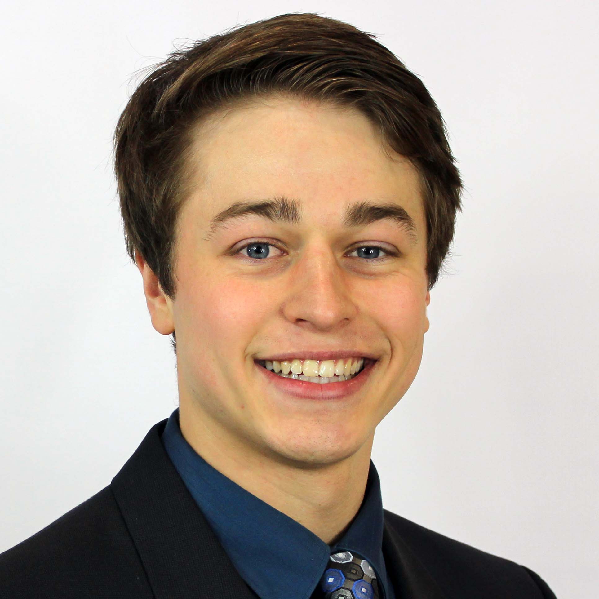 A PhD student wearing a dark blue shirt with a black sports coat and tie