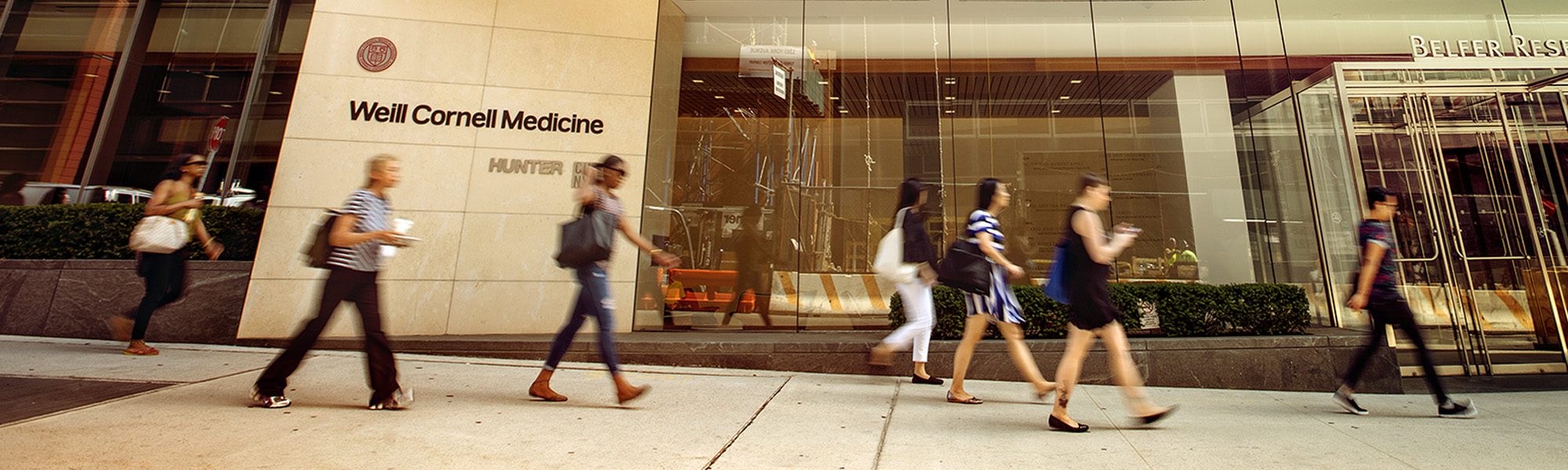 People walk on the sidewalk outside weill cornell medicine in new york city.