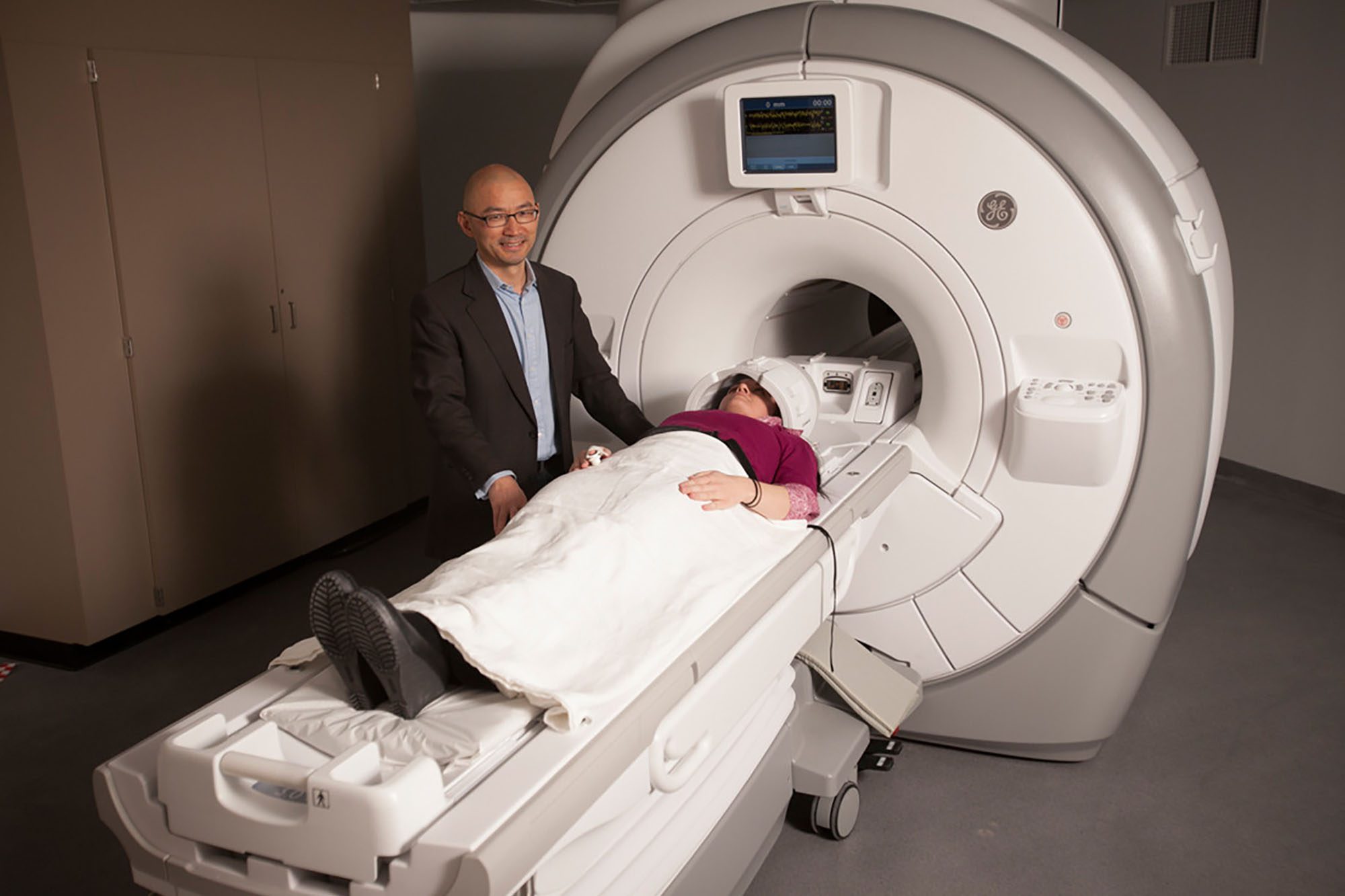 Faculty Yi Wang stands with patient in front of MRI machine