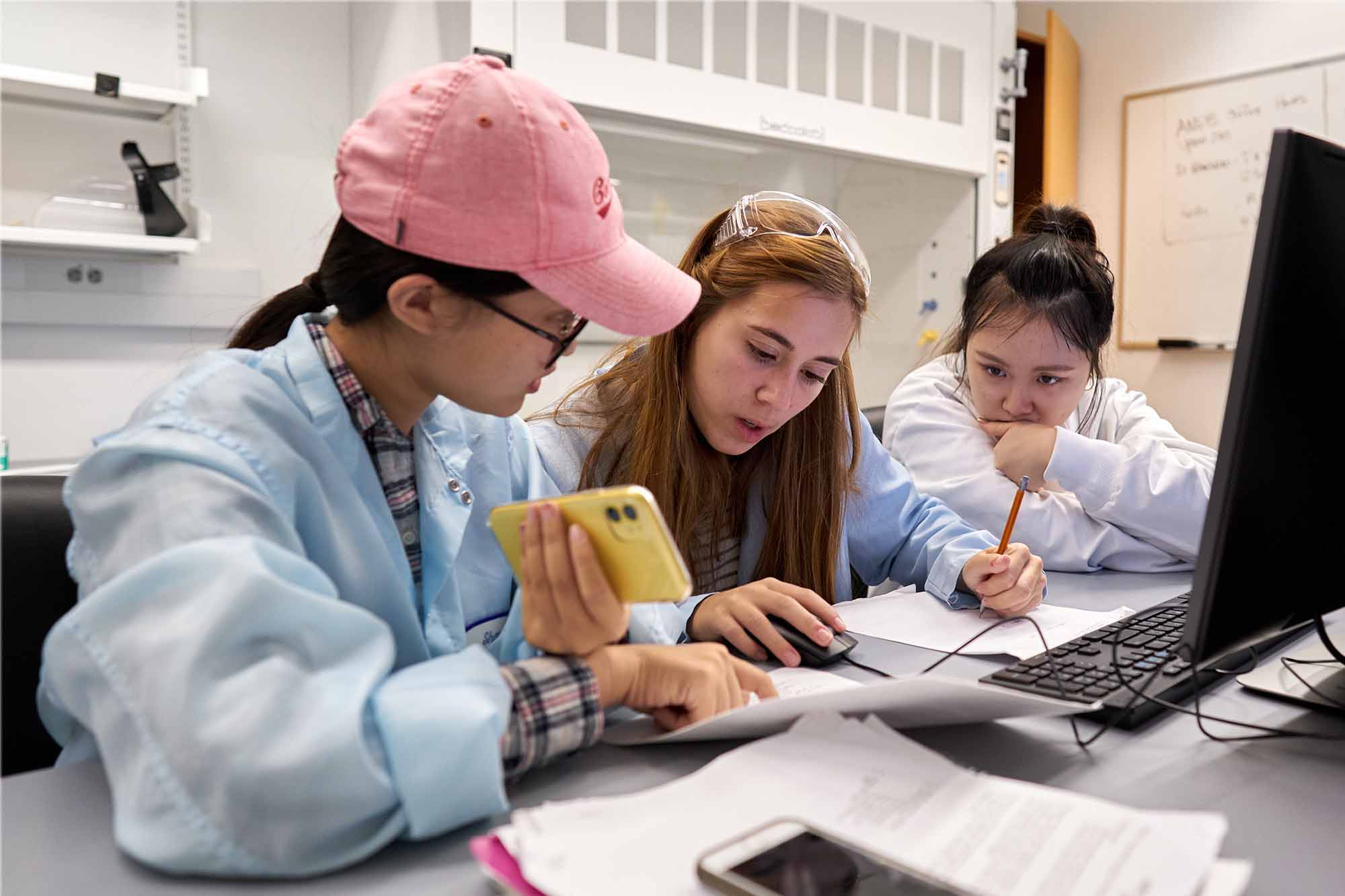 Undergraduate students work together in lab with computers and calculators
