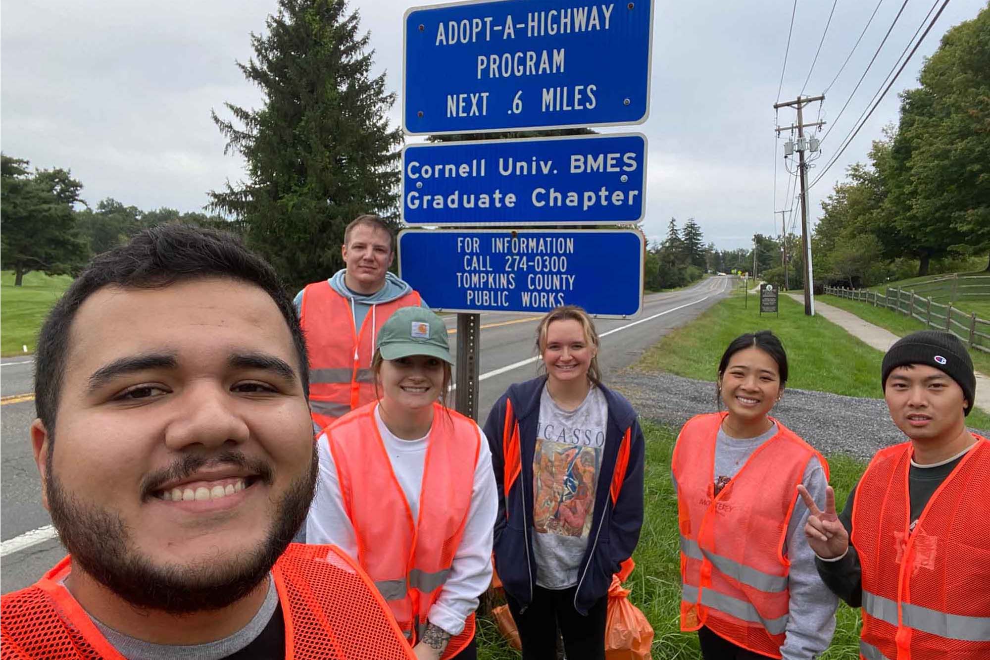 BMES graduate students stand together next to highway sign as part of cleanup outreach event.