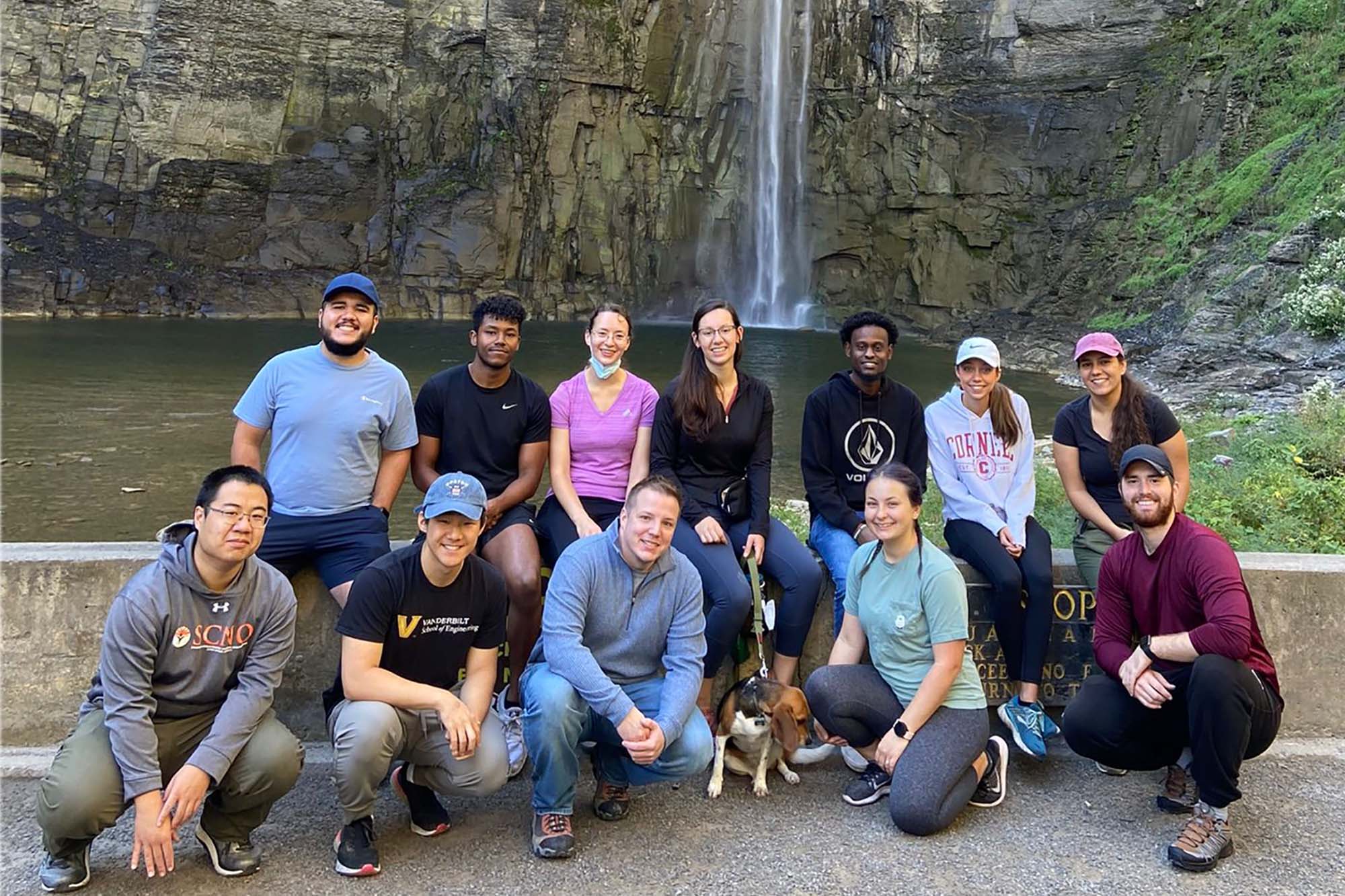 Graduate students BMES group hike stand together in front of Taughannock Falls.