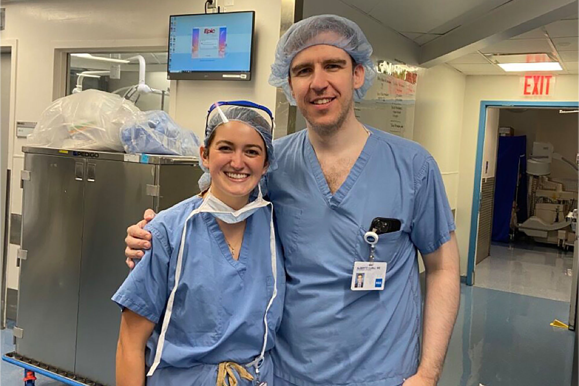 Ph.D. student Andi Garcia-Ortiz and surgeon Alberto Carli stand together wearing scrubs at Weill Cornell Medicine clinical immersion.