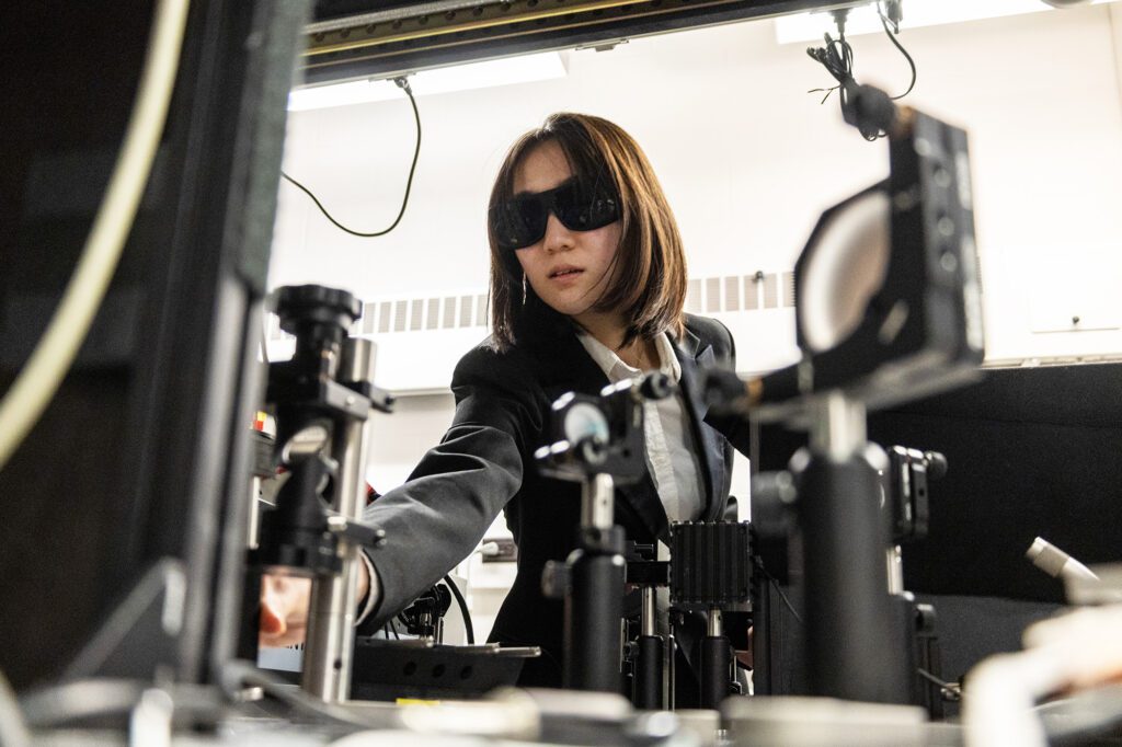 Undergraduate Hazuki Takahashi wearing sunglasses works in Chris Xu optics lab on multi-photo microscope development and imaging.
