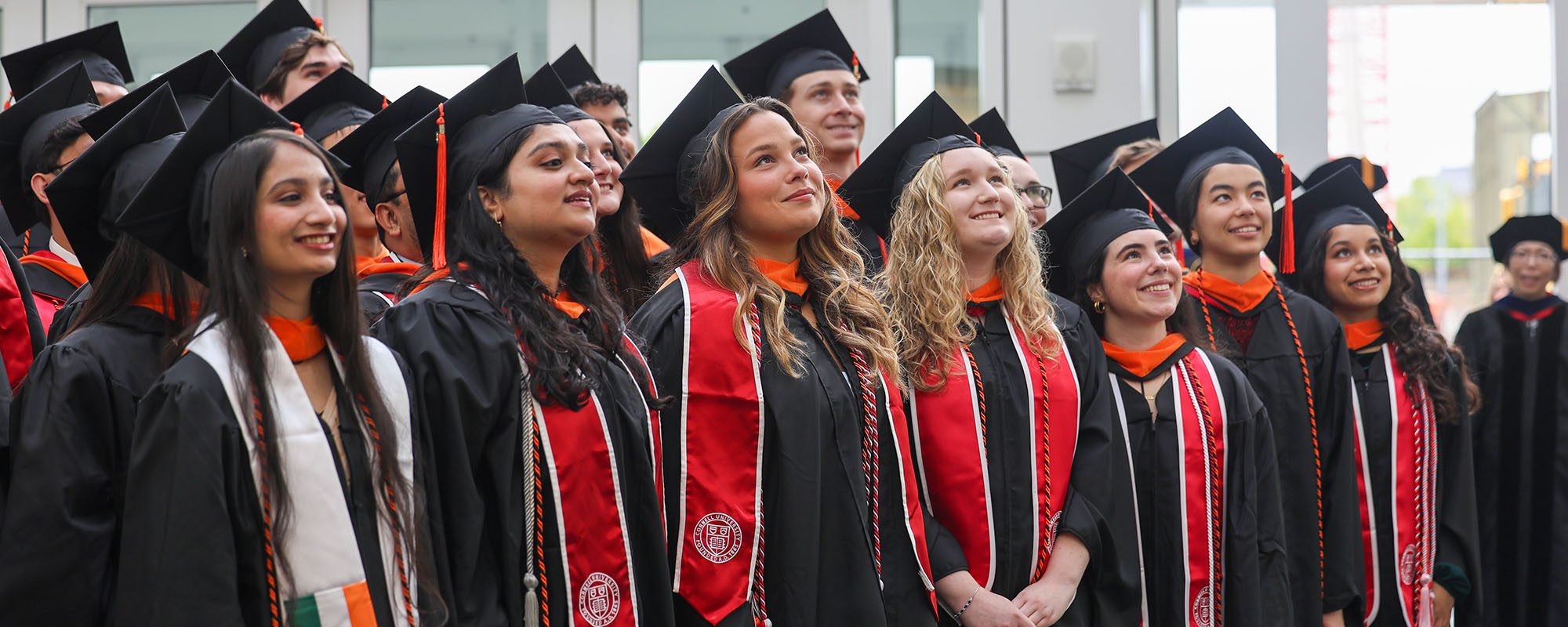 MEng graduates in regalia look up at photographer in Weill Hall 2025.