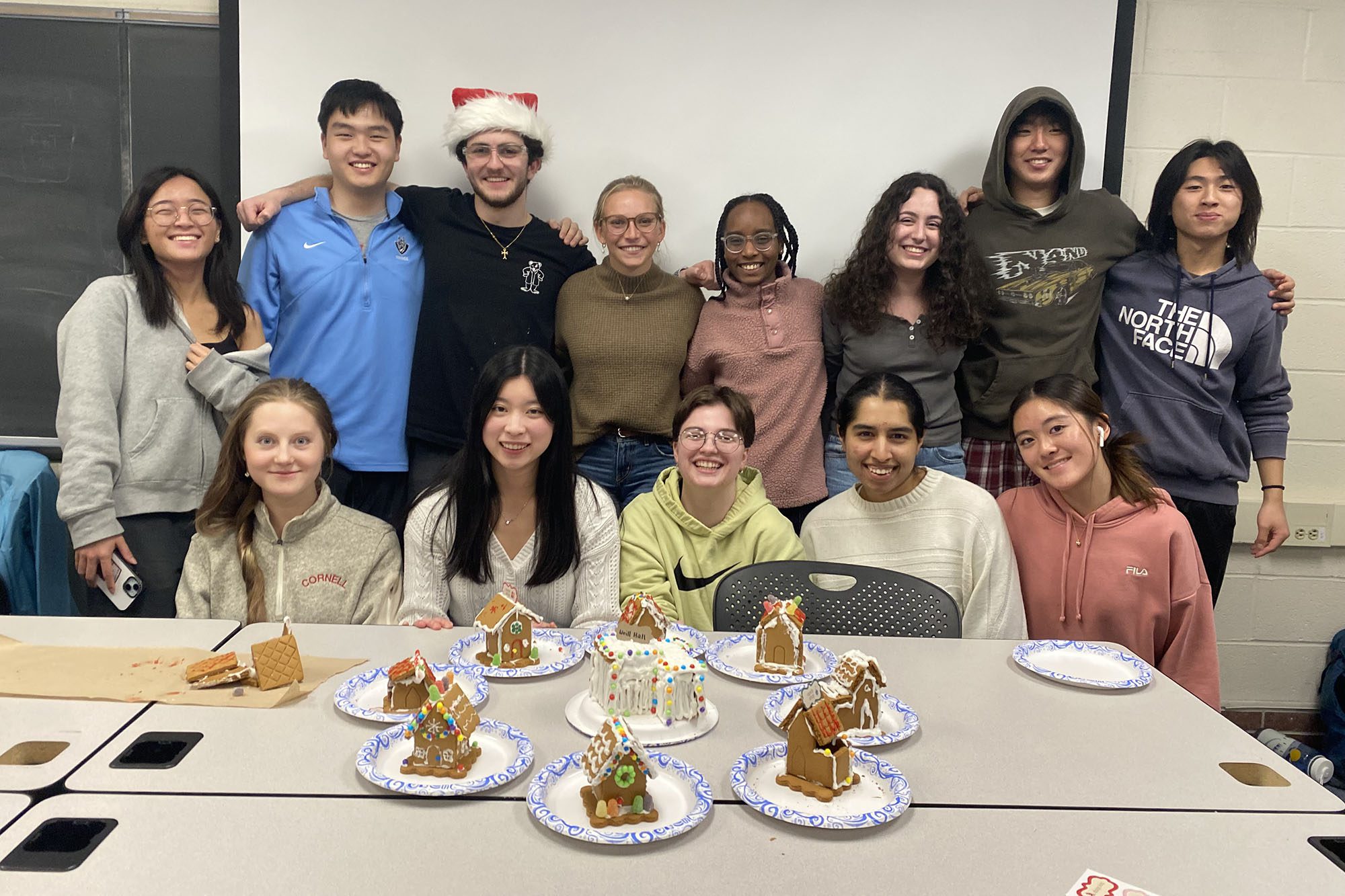 Undergraduates sit together with decorated gingerbread houses.