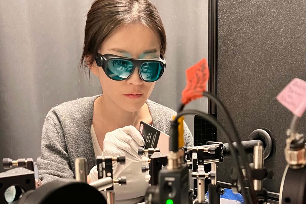 Kwan lab postdoc Lingxiao Shao wears safety glasses in optics lab working with lasers.