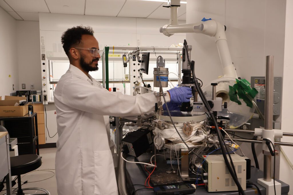Jeremiah James in lab setting up the optical microscope above the CDP reactor to monitor particle production in-situ.