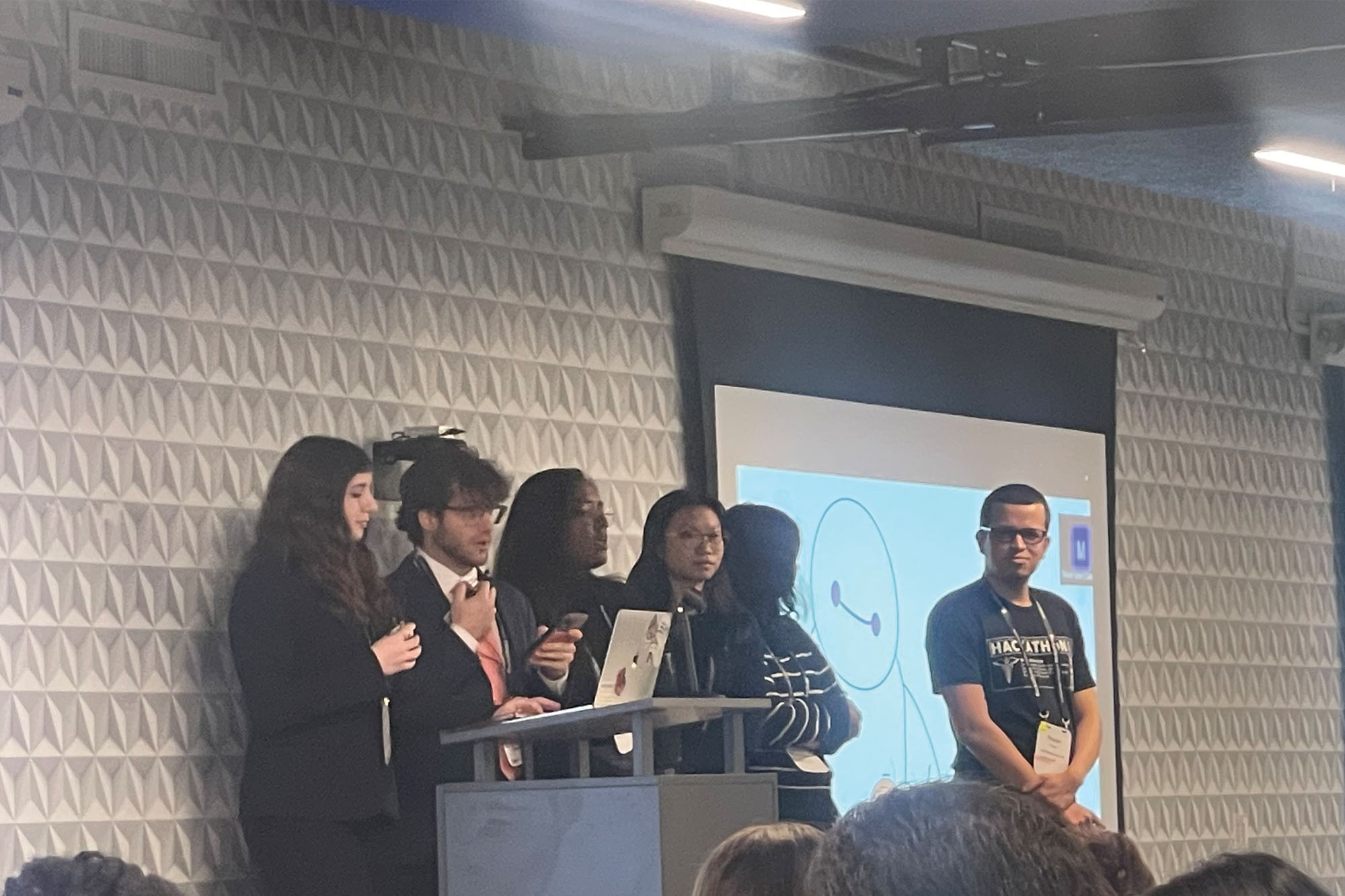 MEng student Maddie Slavett stands with team in front of screen to present their BabyMax project at the 2024 Cornell HealthTech Hackathon.