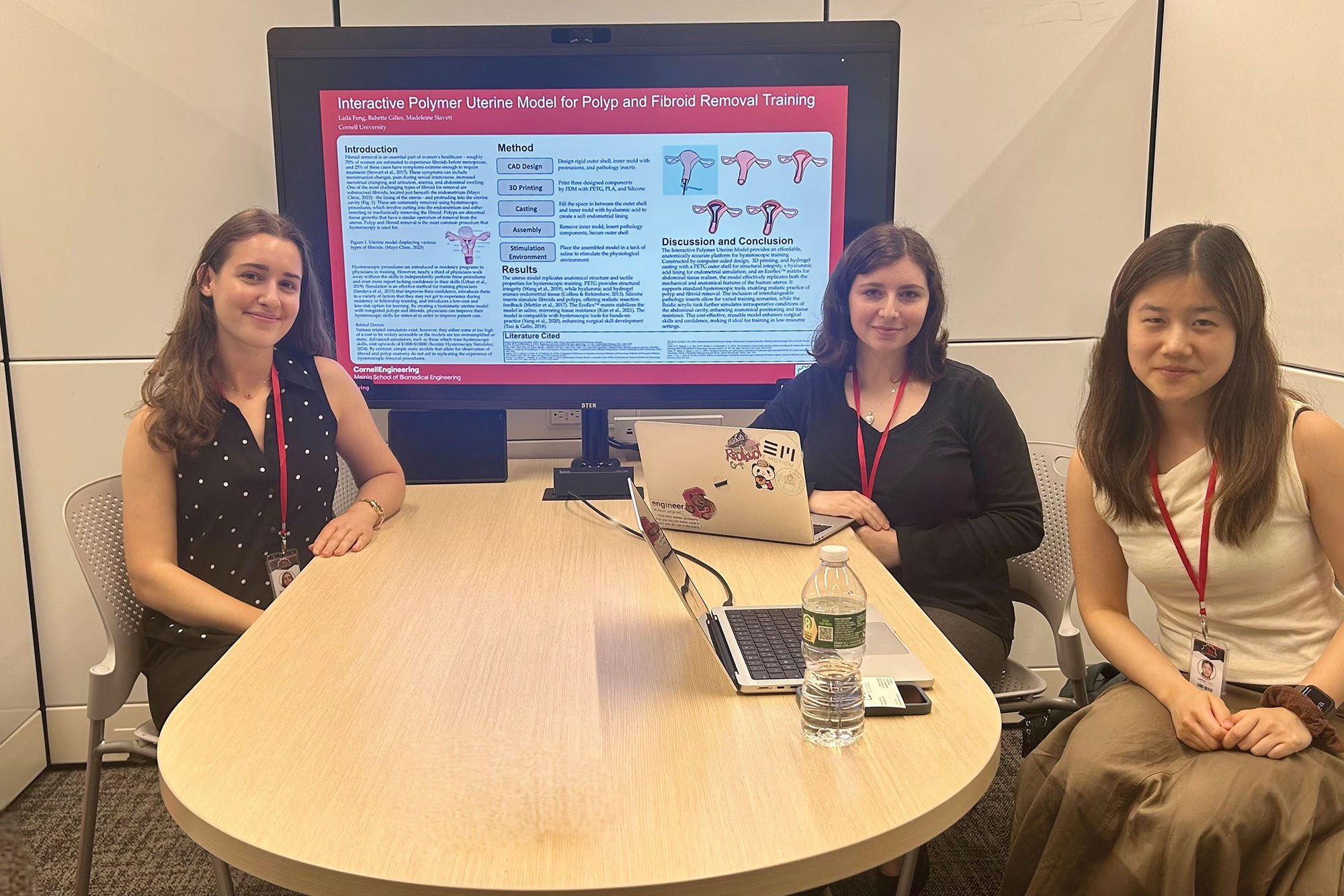 Maddie Slavett and meng design team sit together at table to present their MEng presentation on computer screen in Tang Hall design suite.