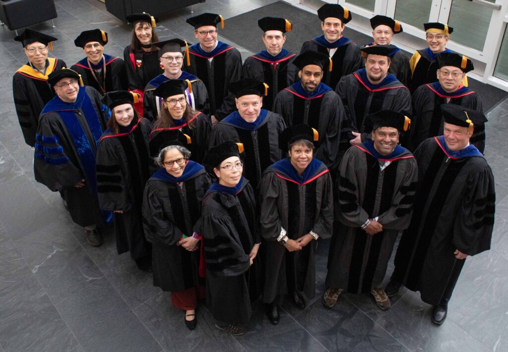 Meinig School faculty stand together in regalia in the Weill Hall atrium on the 2026 commencement day.
