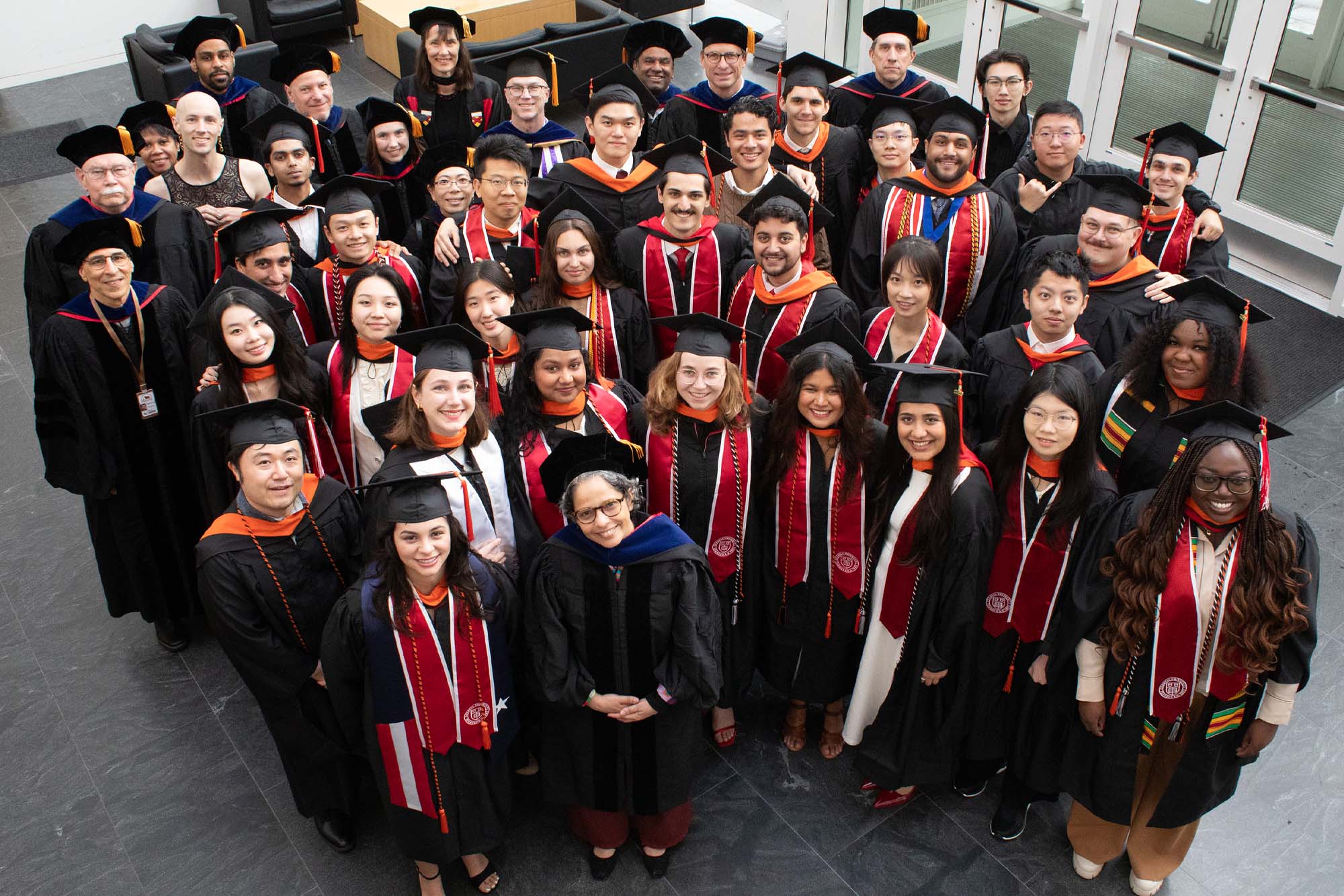 The 2026 biomedical engineering graduating class and faculty standing together in regalia in Weill Hall Atrium.