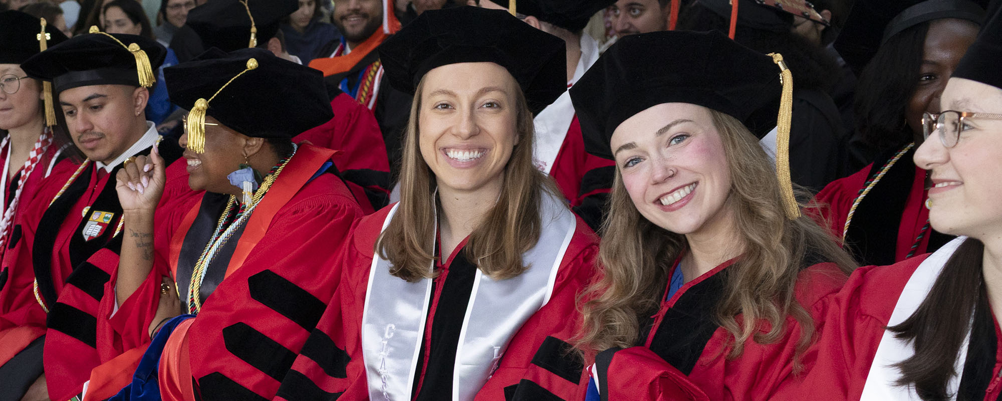 Ph.D. 2026 graduates Maggie Elpers and Brooke Filanoski sit in regalia at the commencement ceremony.