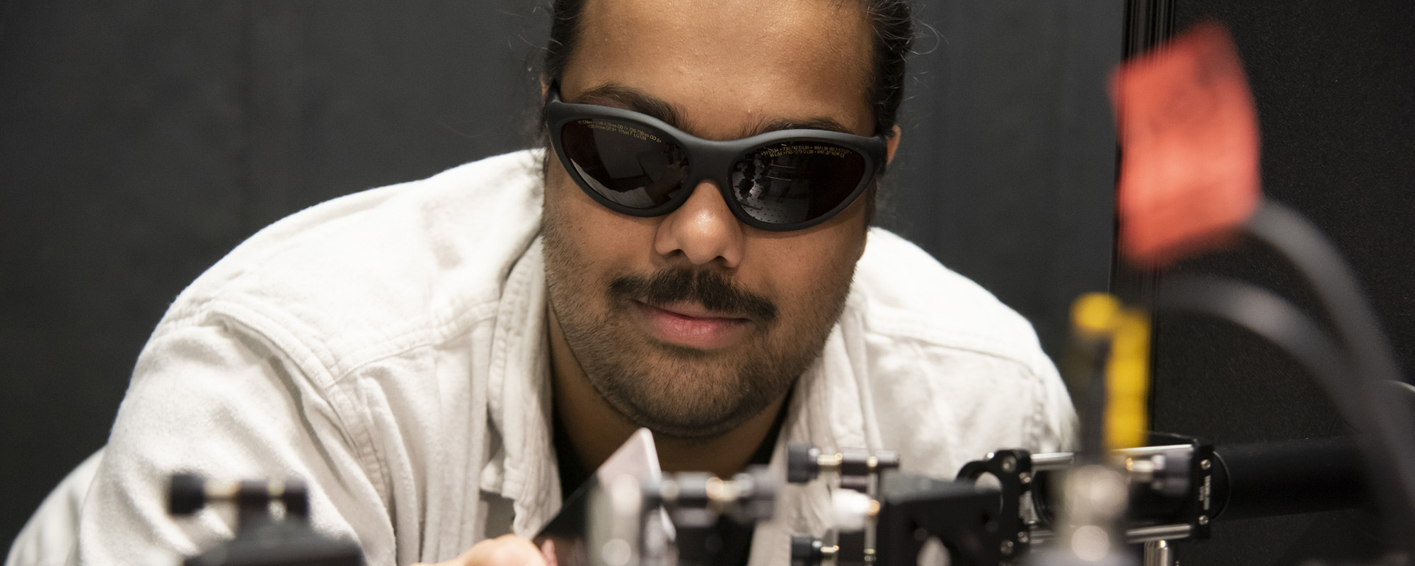 Graduate student works with lasers in optics lab in Weill Hall