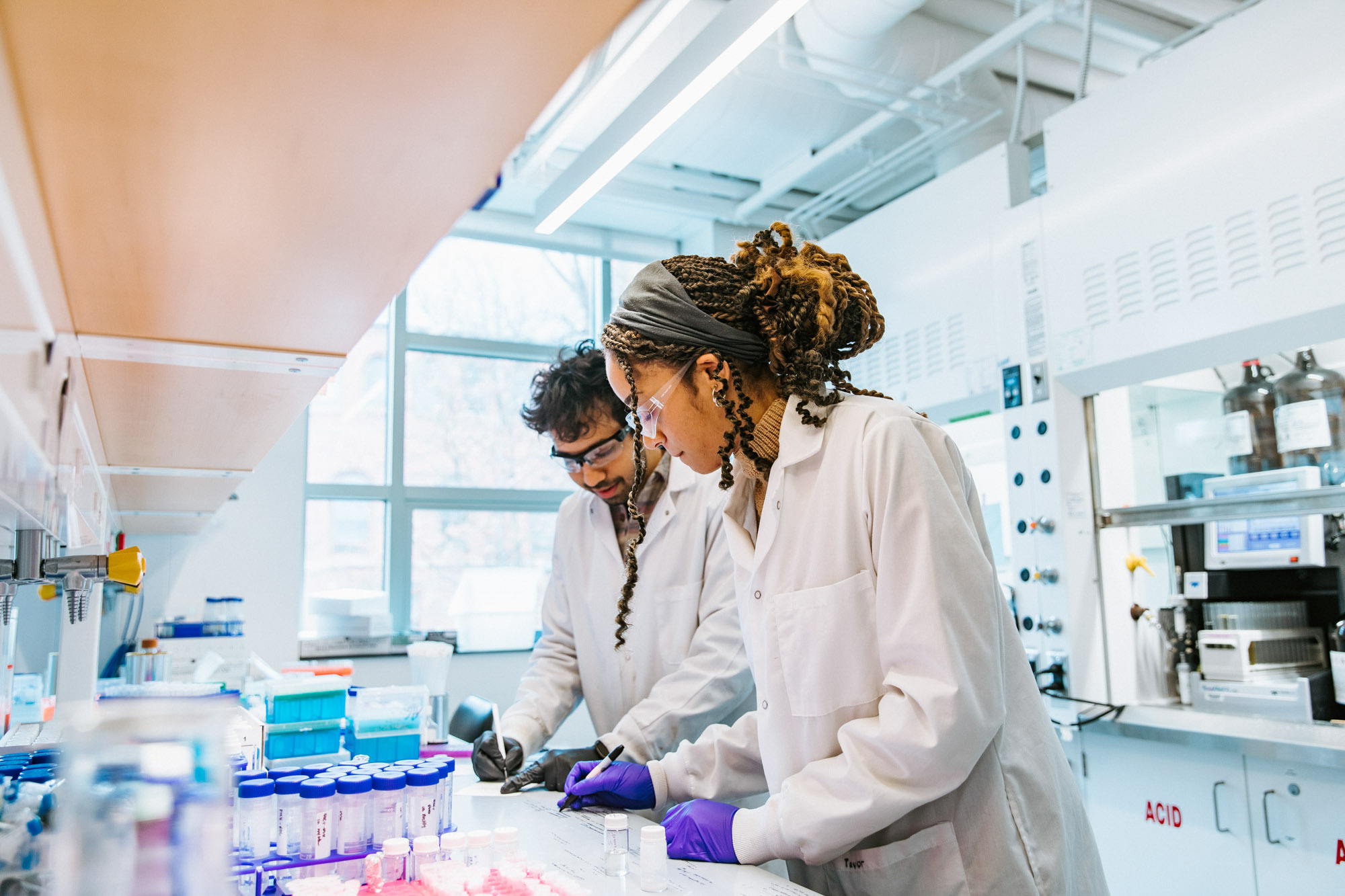 two researchers in lab coats conducting an experiment in the Alabi Lab.