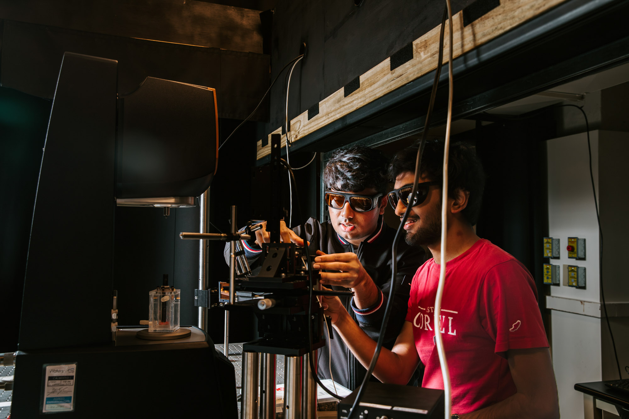 Two students wearing safety goggles doing research in professor Sarah Hormozi's lab