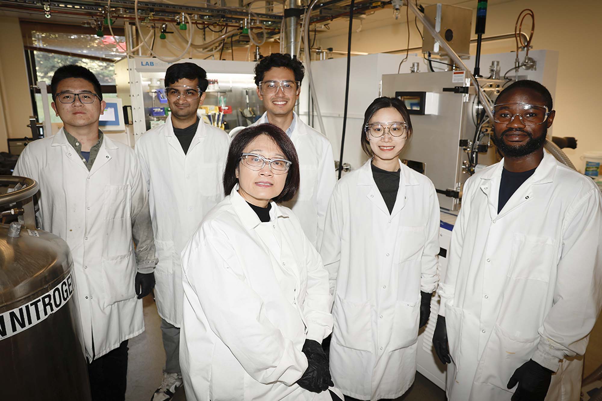 Qiuming Yu and lab group students stand together in lab coats.