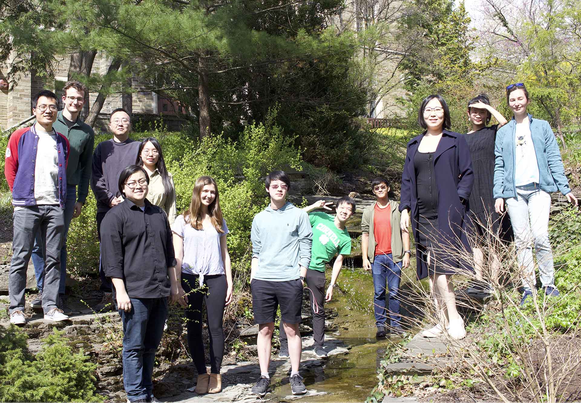 Sijin Li lab members stand together outside on path by stream.