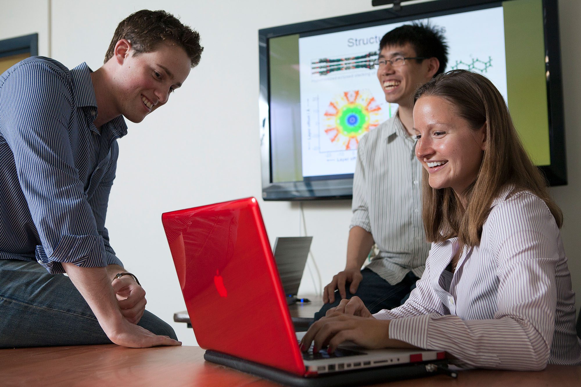 MEng students work around laptop in a group.