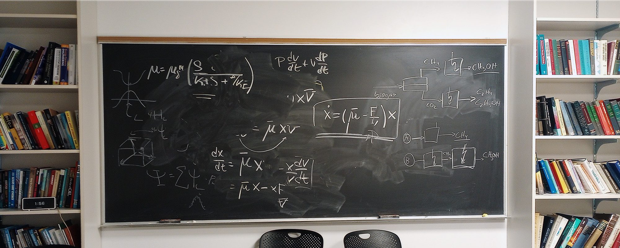 Olin Hall blackboard with figures, flanked by bookshelves.