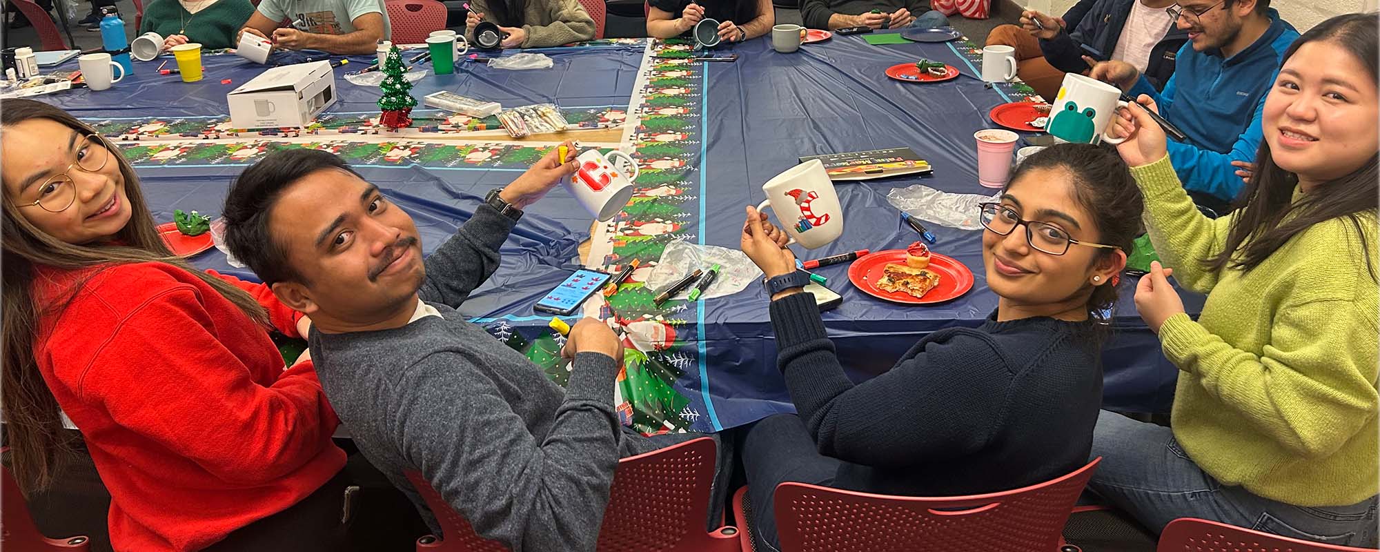 Students sit together at holiday mug decorating event in olin hall.