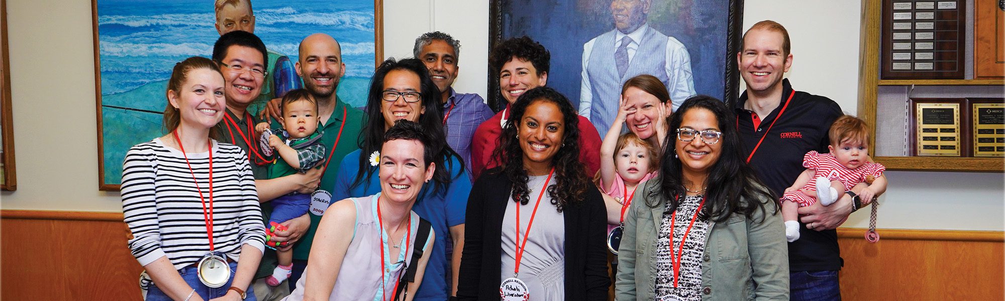 Alumni stand together with kids in a group in front of R.F. Smith portrait.