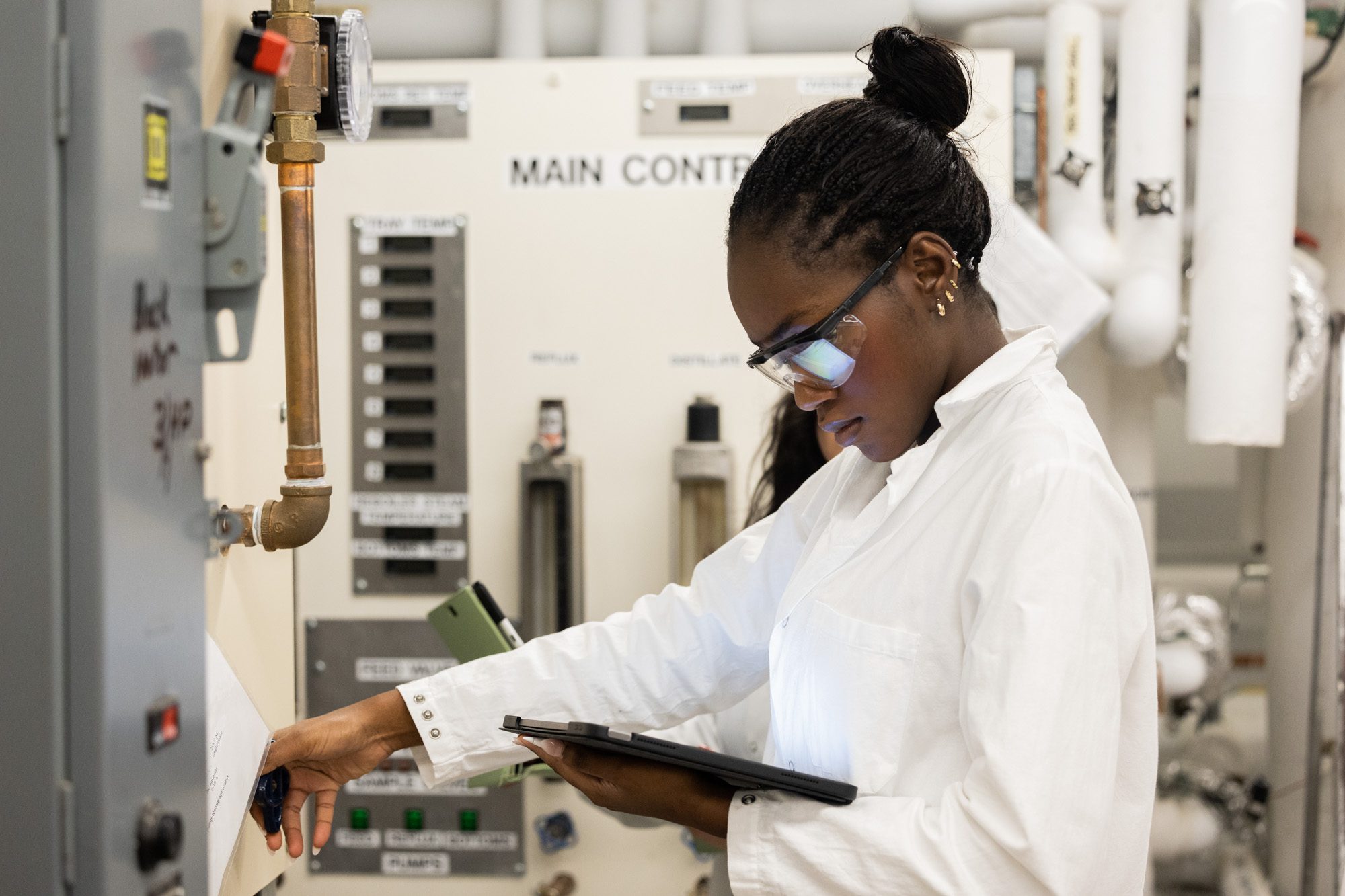 Undergraduate student wearing lab coat and safety glasses work in the Olin Hall Unit Operations Lab.