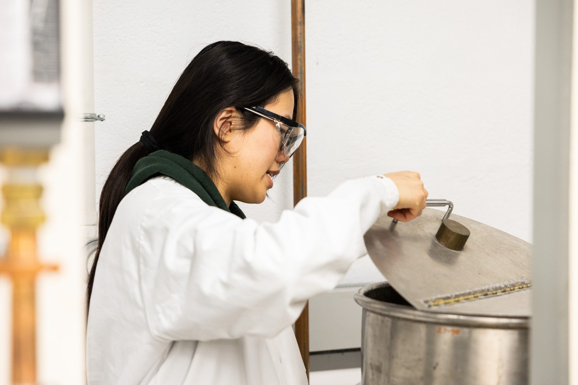 Undergraduate wearing lab coat works in the Olin Hall Unit Operations Lab.