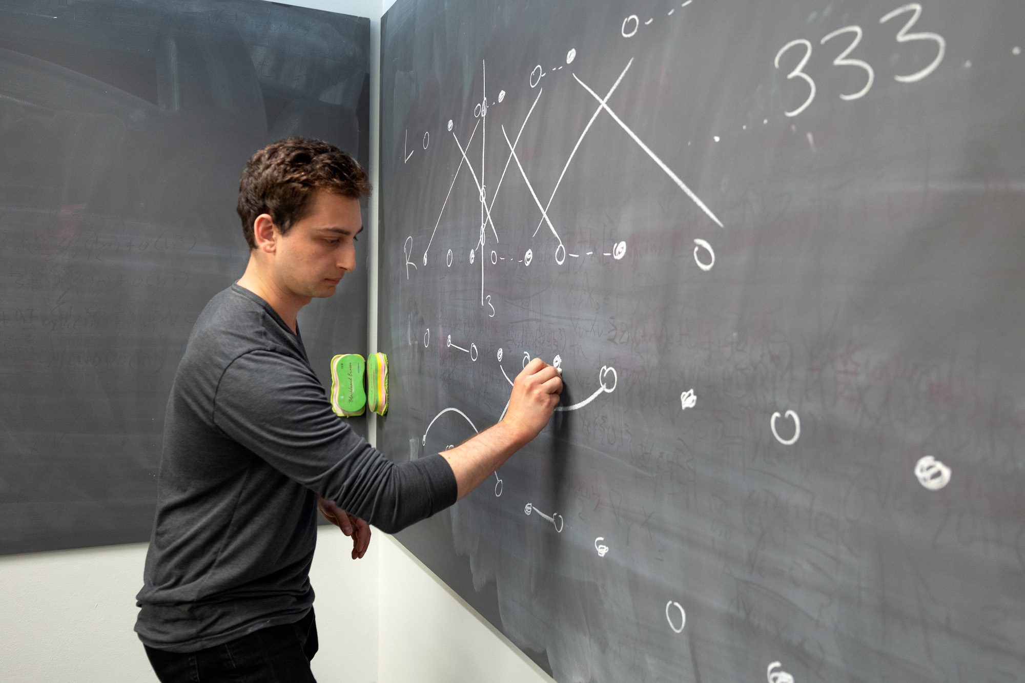 Student drawing figures and numbers on a black board.