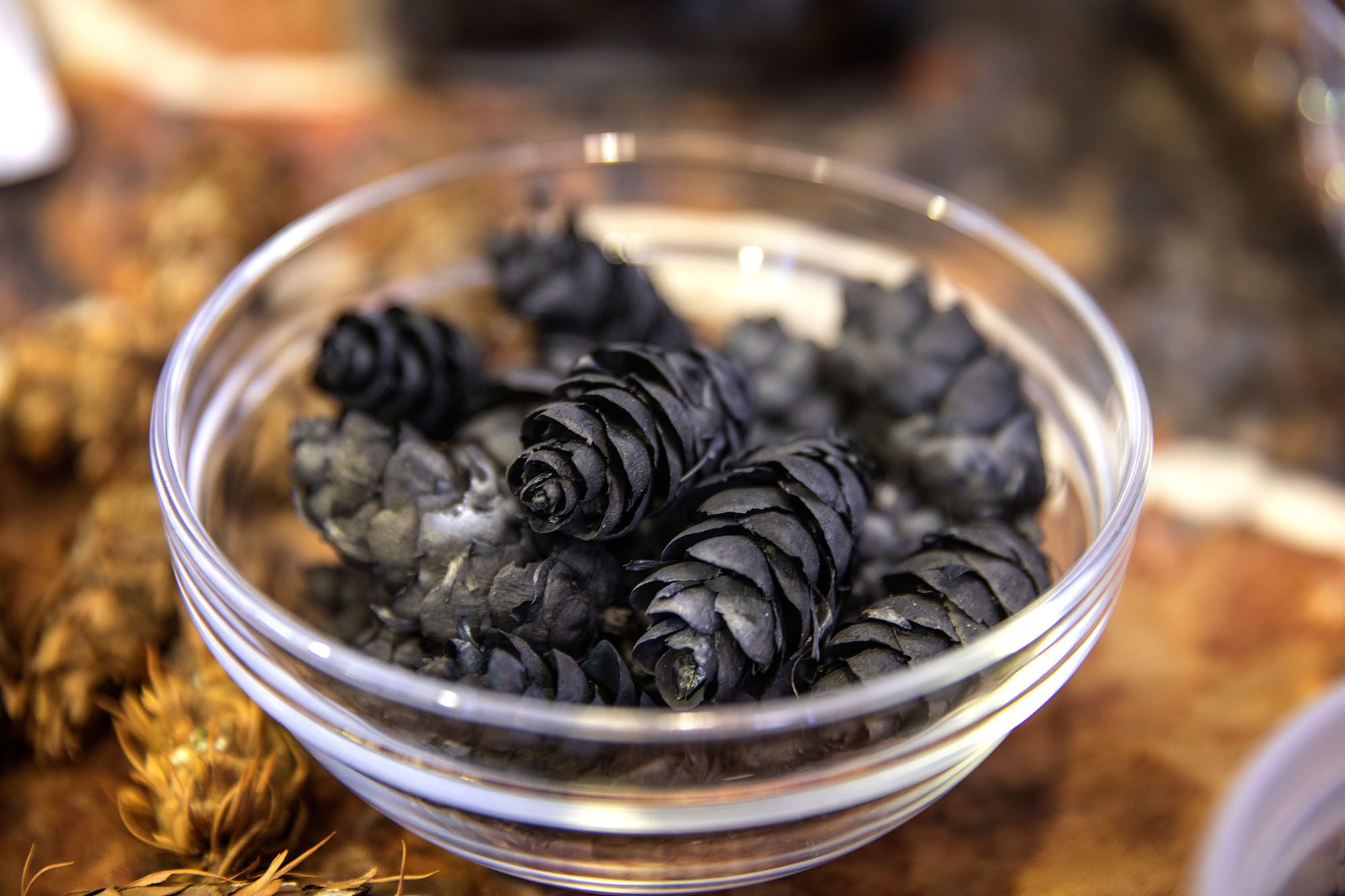 A bunch of pine cones in a glass bowl.