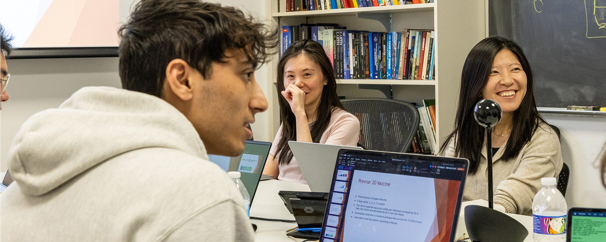 Rong Yang and MEng Students work at table with laptops on their immersive capstone project.