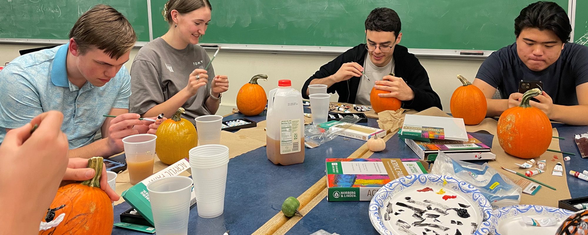 A group of people sitting at a table with pumpkins