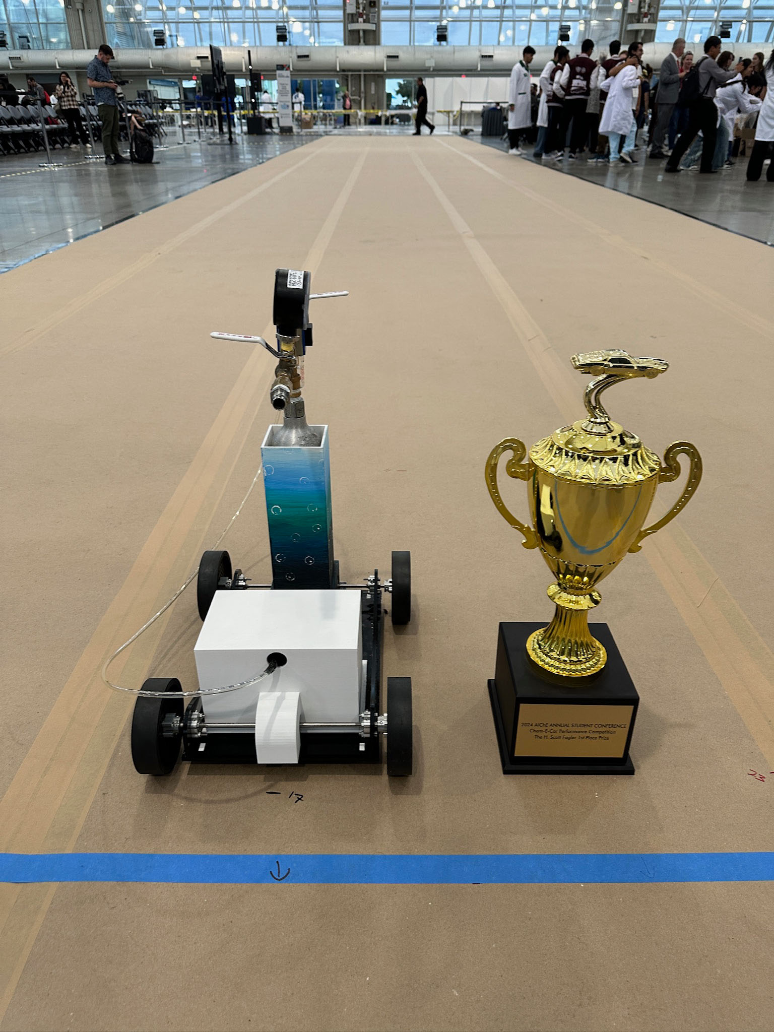 The ChemE car sits on runway next to trophy.