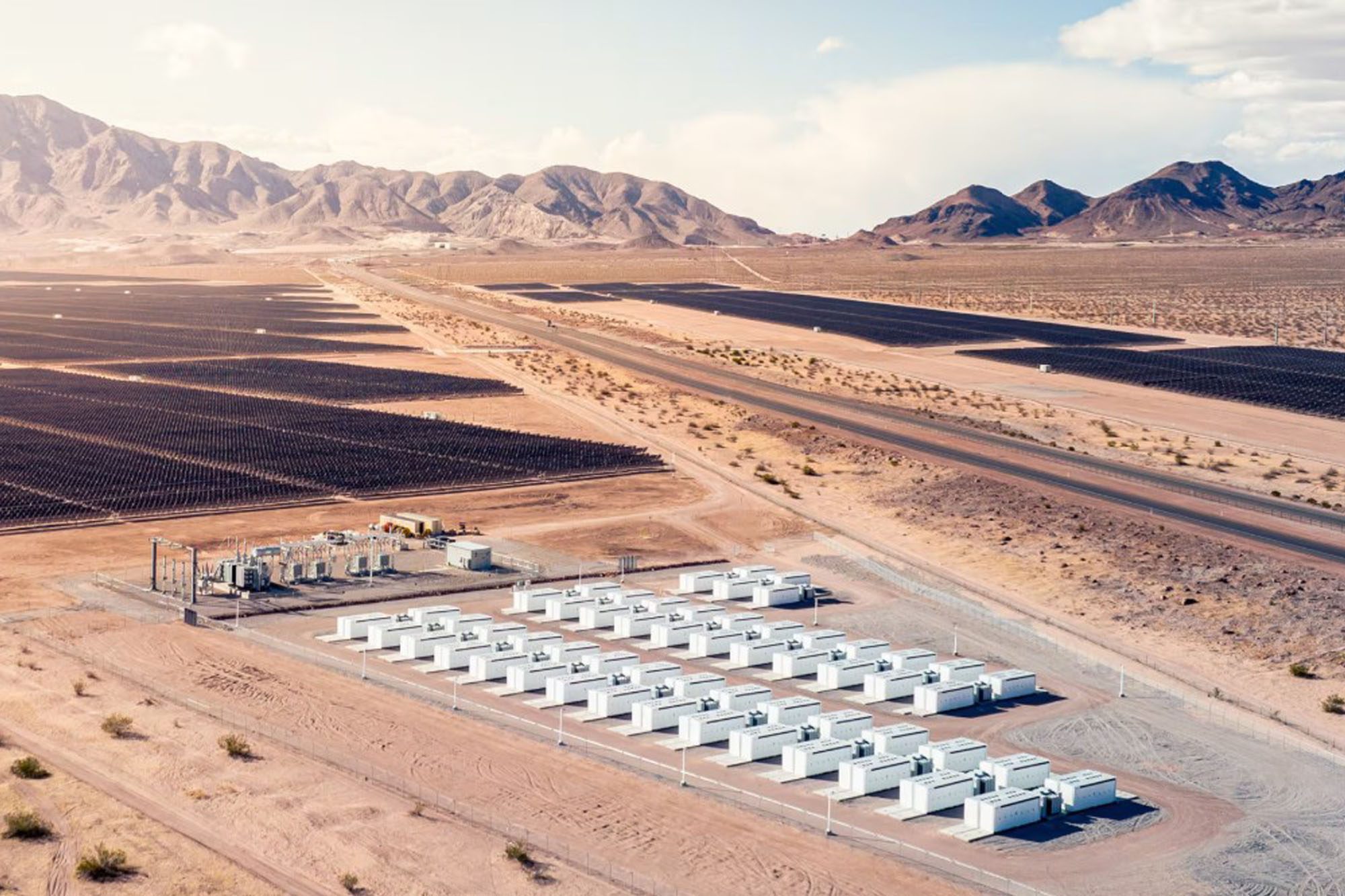 Battery storage site buildings in a desert with mountains behind.