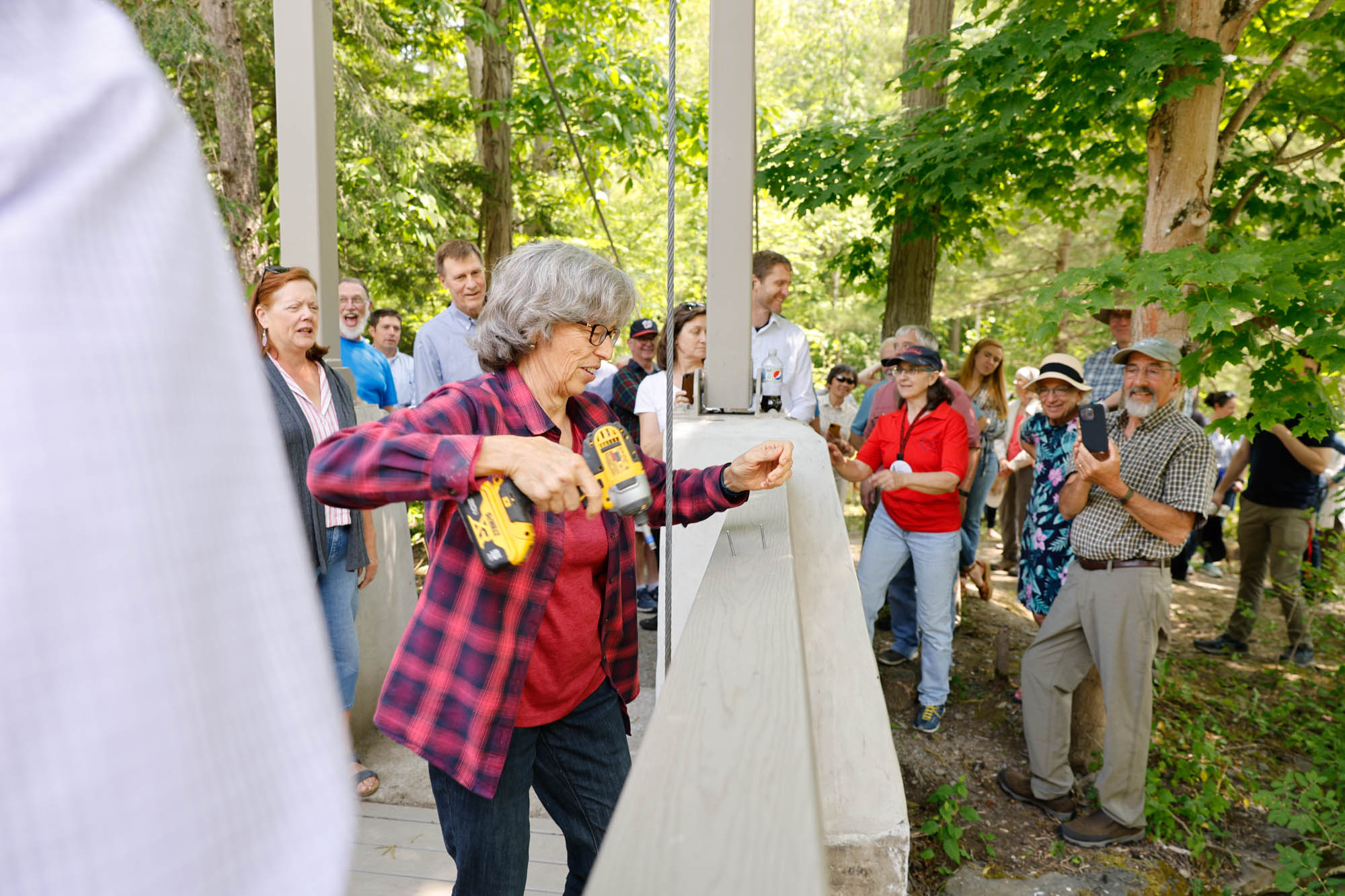 Person uses drill at Flat Rock Bridge while a group of other people watch