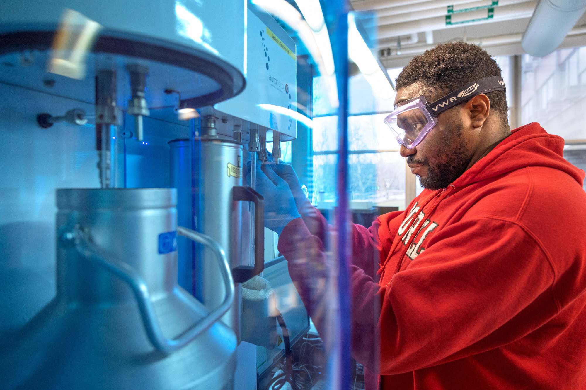Graduate Student Prince Ochonma wears safety goggles while operating a machine in a lab.
