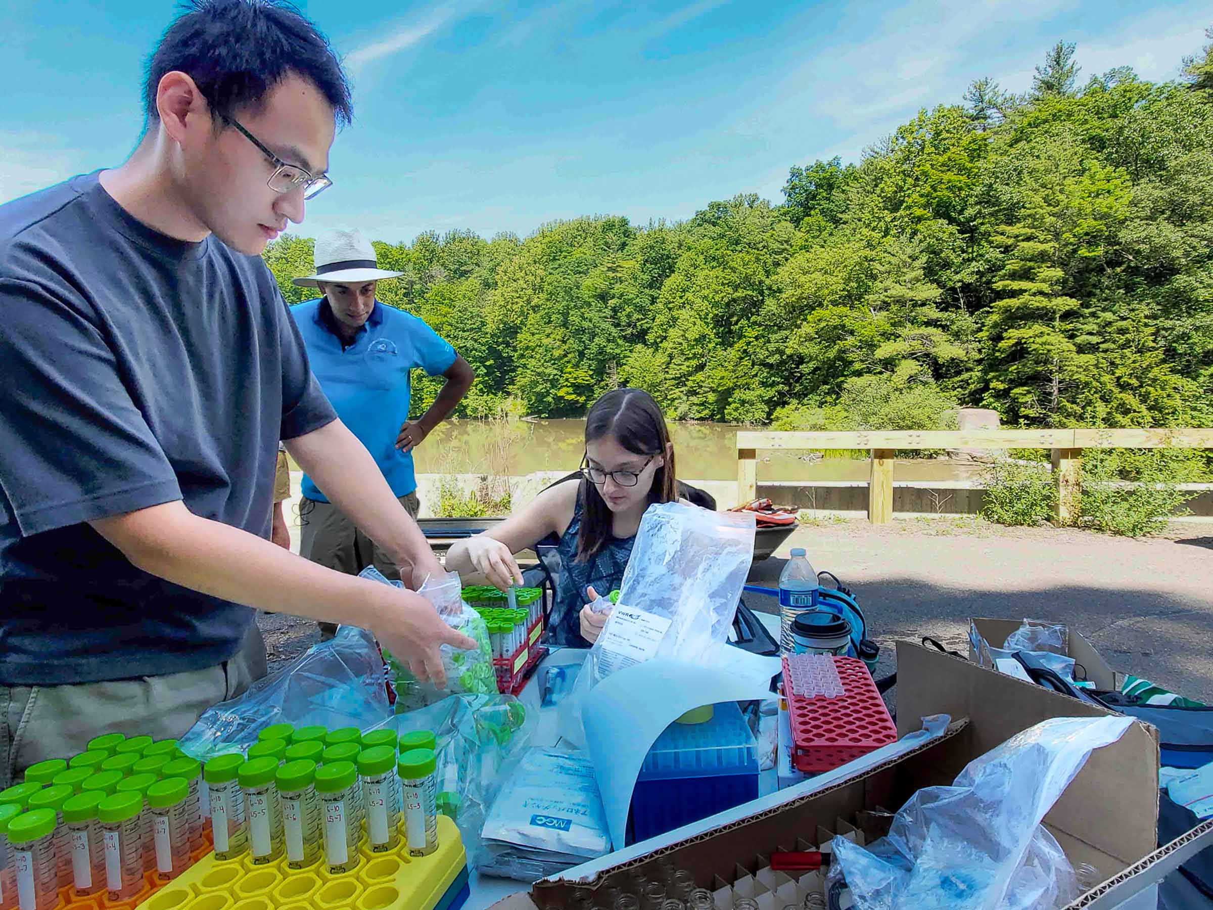 Professor Matt Reid and students organize vials for collecting water samples near water reservoir in Ithaca