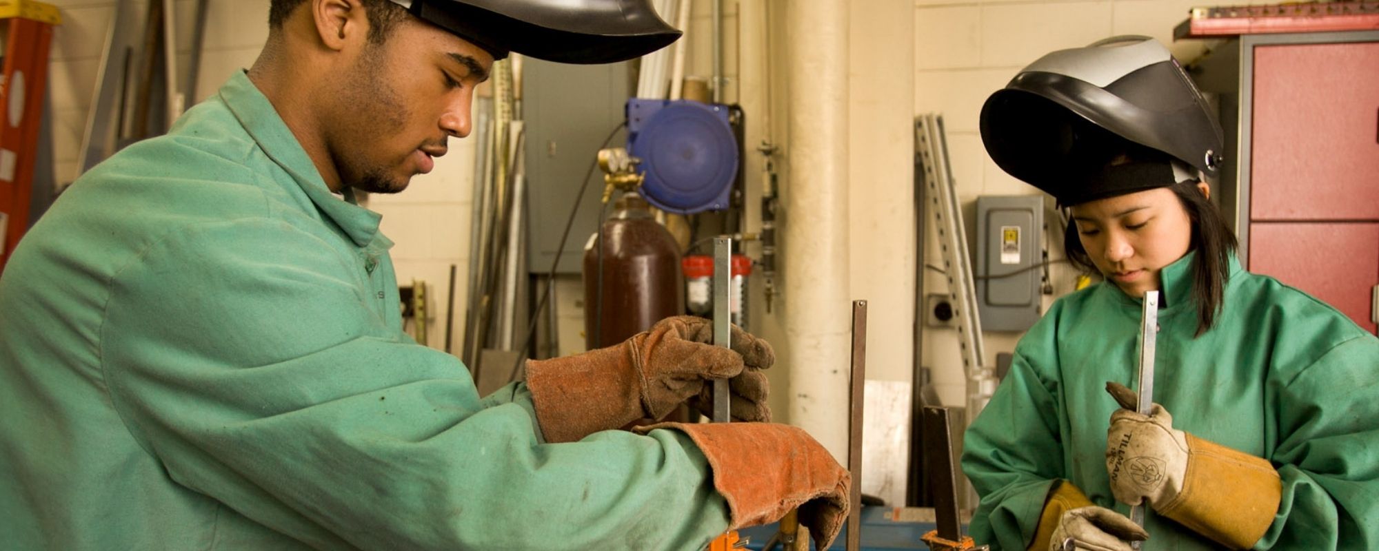 Two students wearing welding hoods working in a civil and environmental engineering lab