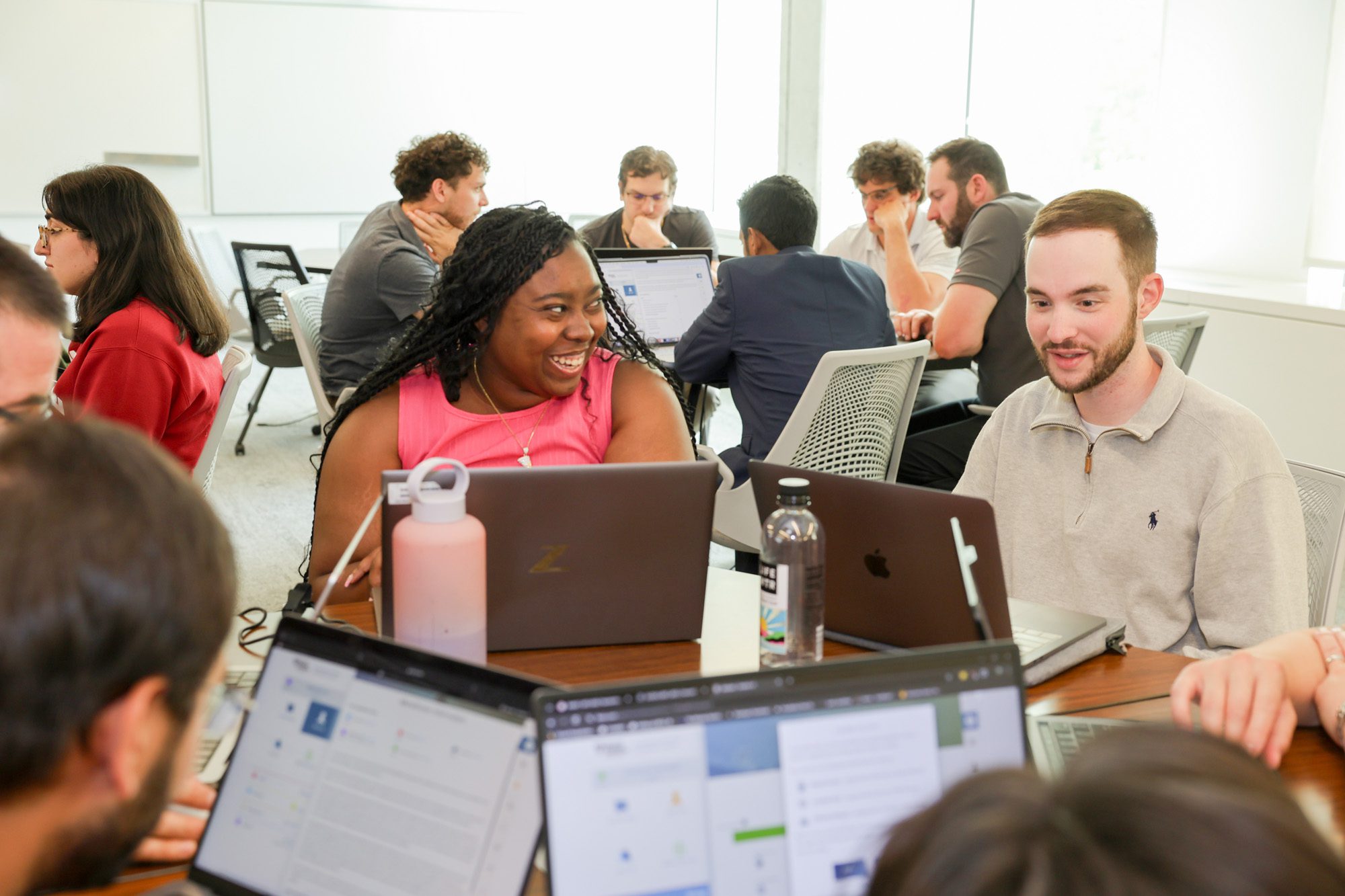 Distance learning students sitting around tables working on their laptops during their residential experience