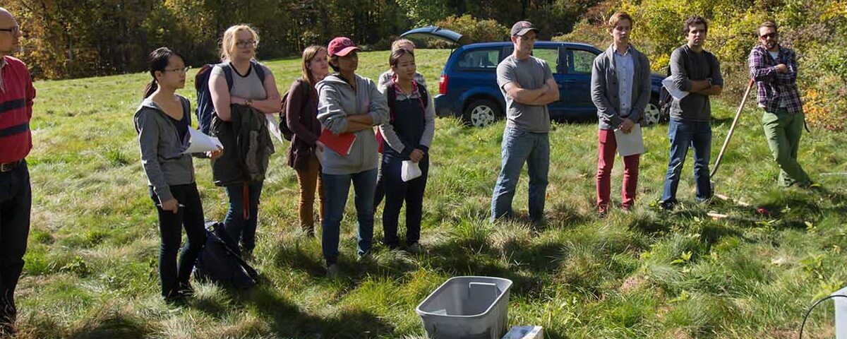 students stand in a field on North Campus as they prepare to bury seismic sensors
